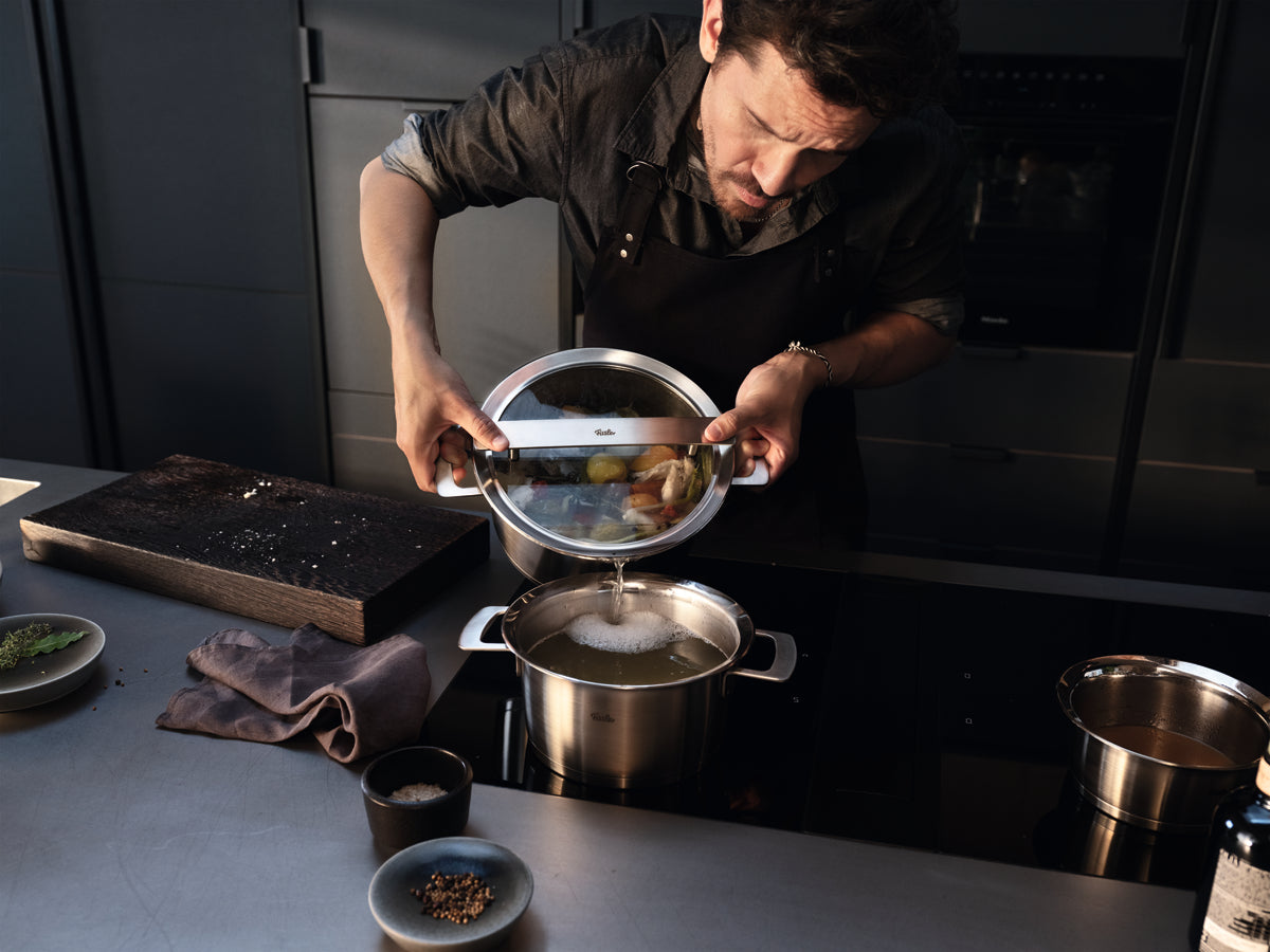 Ein man cooks with the 5-piece Cookware Set Phi Collection® by Fissler - precise, innovative German Cookware on a modern stovetop.