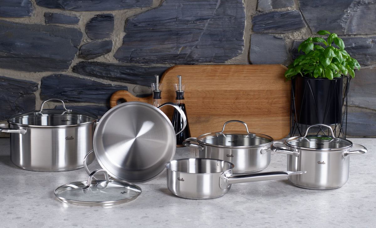 Fissler San Francisco Topf-Set mit superthermischem Boden für Induktion auf der Theke, mit Deckeln, Brett, Ölspender & Basilikum.