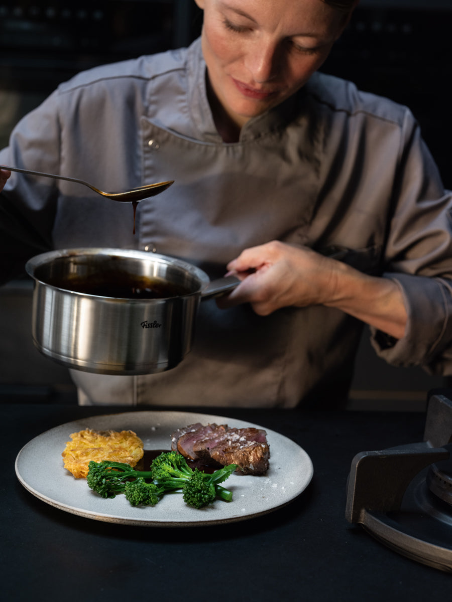 Ein Chefkoch brät ein Steak präzise mit der Fissler Original-Profi Collection® 16 cm Stielkasserolle, die in Deutschland aus 18/10 Stahl hergestellt wird.