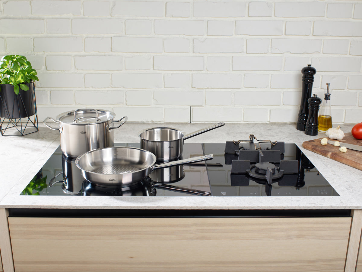 Eine elegante Küche mit Fissler Original-Profi Collection® Kochgeschirr und frischen Zutaten, die deutsche Präzision und zeitloses Design präsentieren.