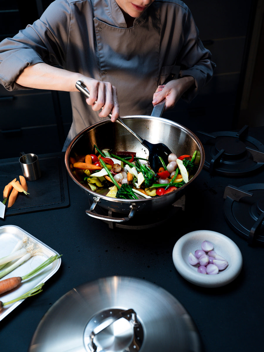 Ein Koch rührt Gemüse im Fissler Original-Profi Collection® Wok 32cm, der in Deutschland mit Präzision und zeitloser Haltbarkeit hergestellt wird.