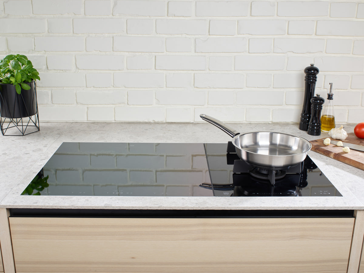 Eine moderne Küche mit Fissler Pure Collection Pfanne auf Induktionskochfeld, frischen Zutaten und dem typischen deutschen Qualitätsdesign.