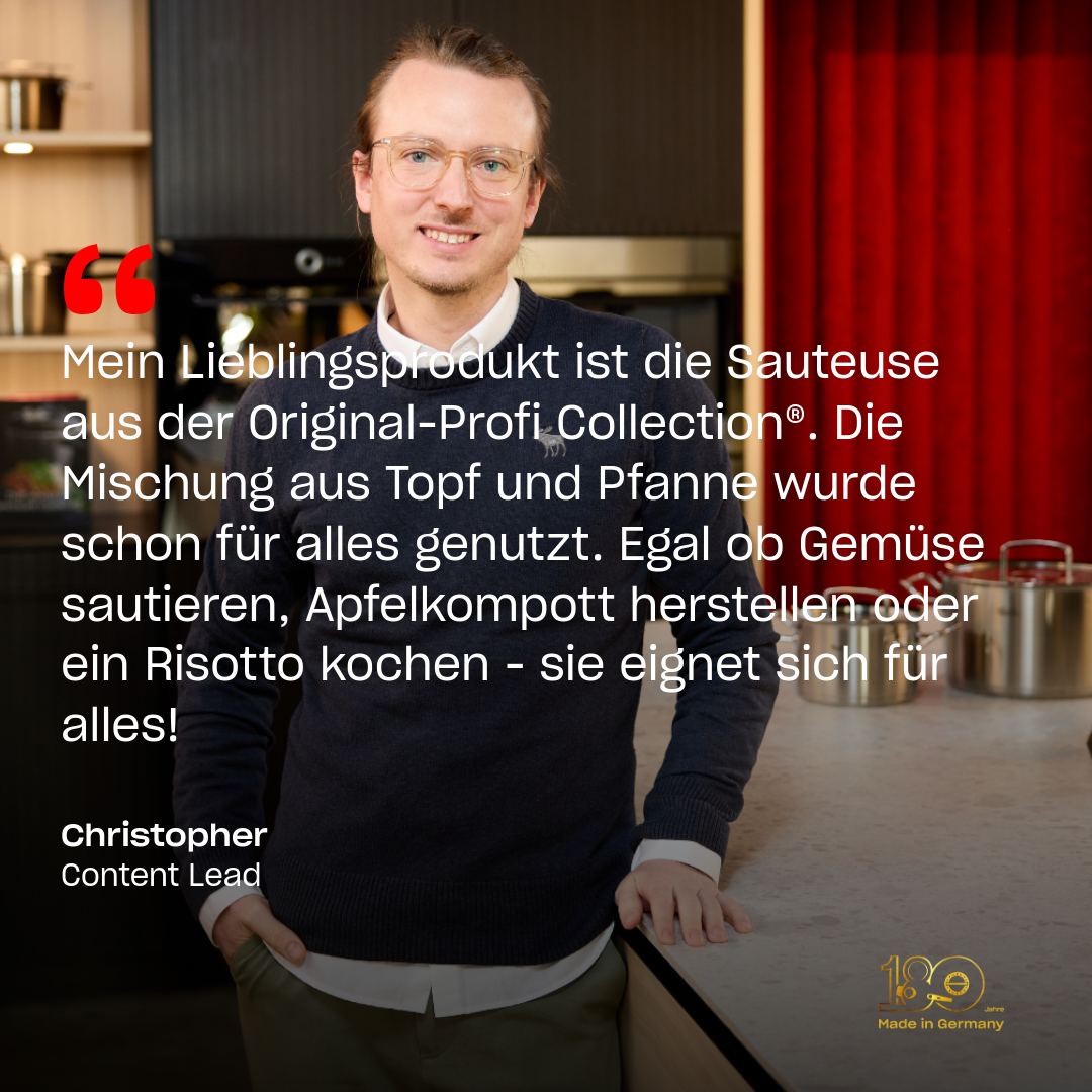 Ein Mann mit Brille und blauem Pullover lächelt durch eine moderne Küche mit Fissler-Töpfen hinter ihm; sein Testimonial ist auf einer Fissler-Sautierpfanne zu sehen.