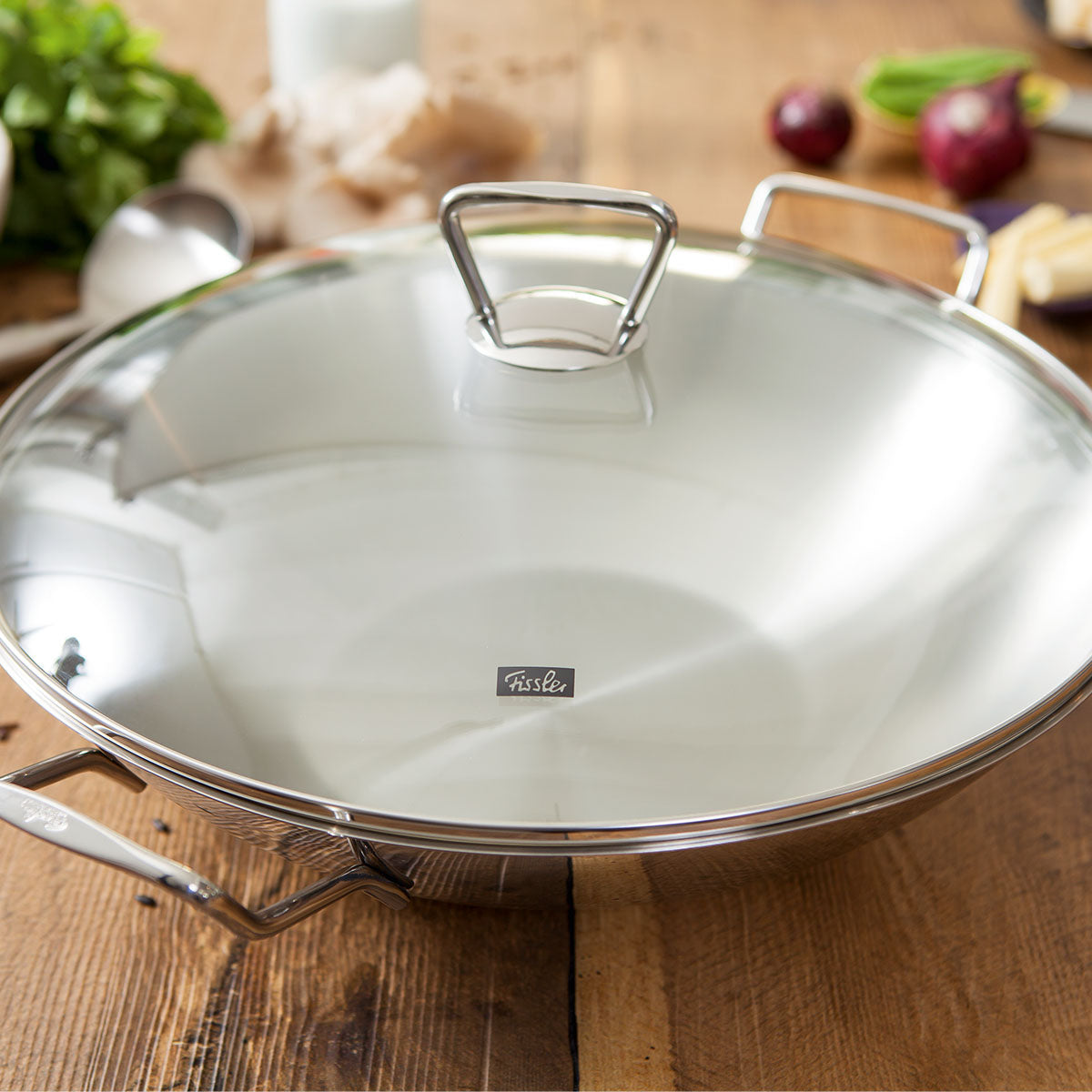 Fissler Kunming Wok mit Glasdeckel 36 cm, Edelstahl, zeitloses Design, auf Holztisch - Qualität "Made in Germany".