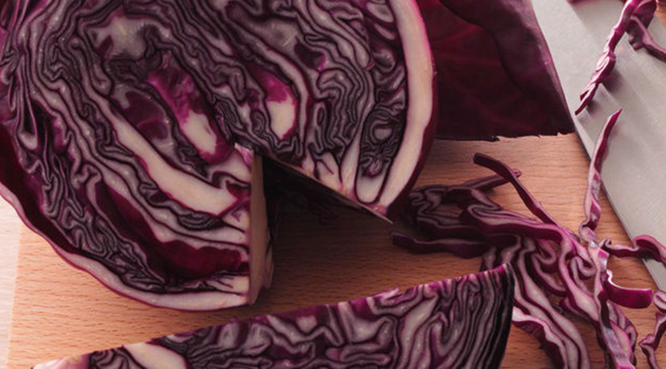 Eine Nahaufnahme von geschnittenem Rotkohl auf einem Holzbrett mit einem eleganten Fissler-Messer, das präzise Schnitte und lebendige Texturen hervorhebt.