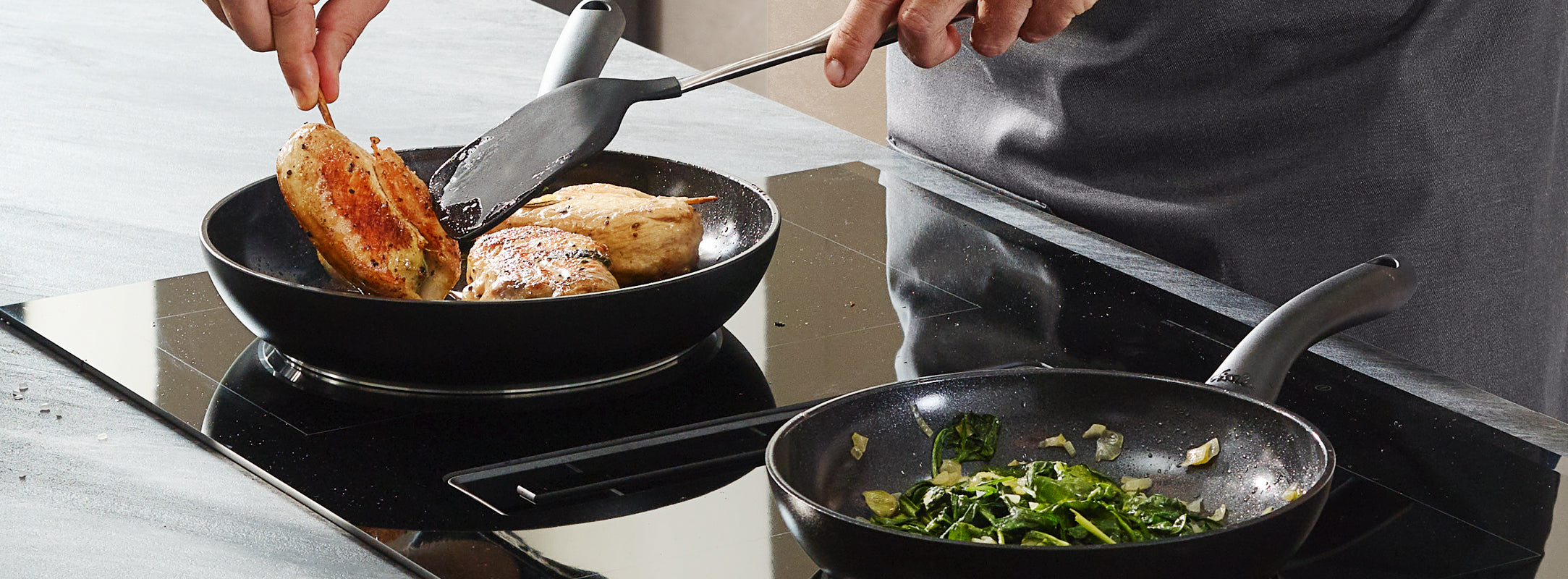 Eine Person bereitet Hähnchenbrüste in einer Fissler-Pfanne zu, während daneben Gemüse und Zwiebeln brutzeln und so deutsche Handwerkskunst demonstrieren.