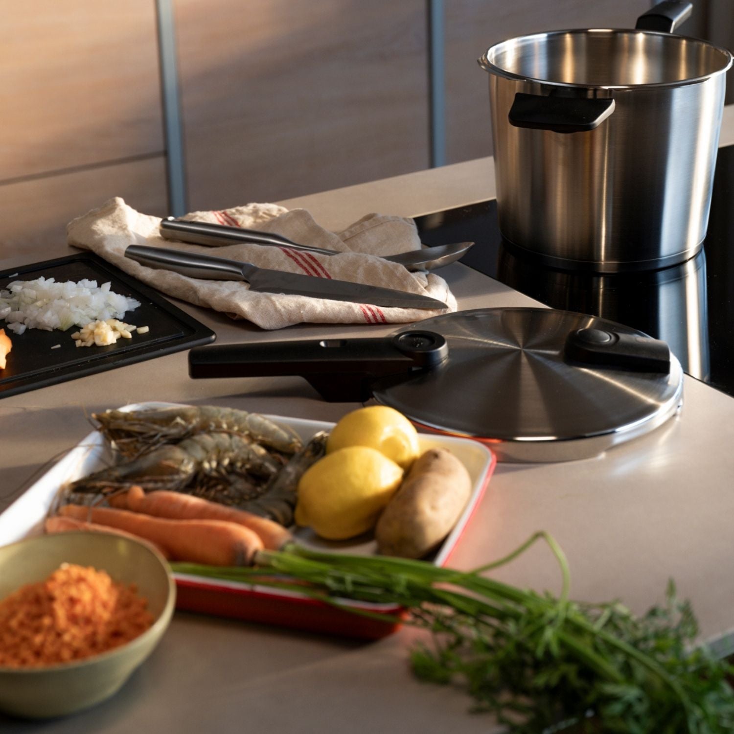 Eine Küchentheke mit Fissler-Edelstahltopf, Schnellkochtopfdeckel, frischen Zutaten und Utensilien, bereit für kulinarische Kreationen.