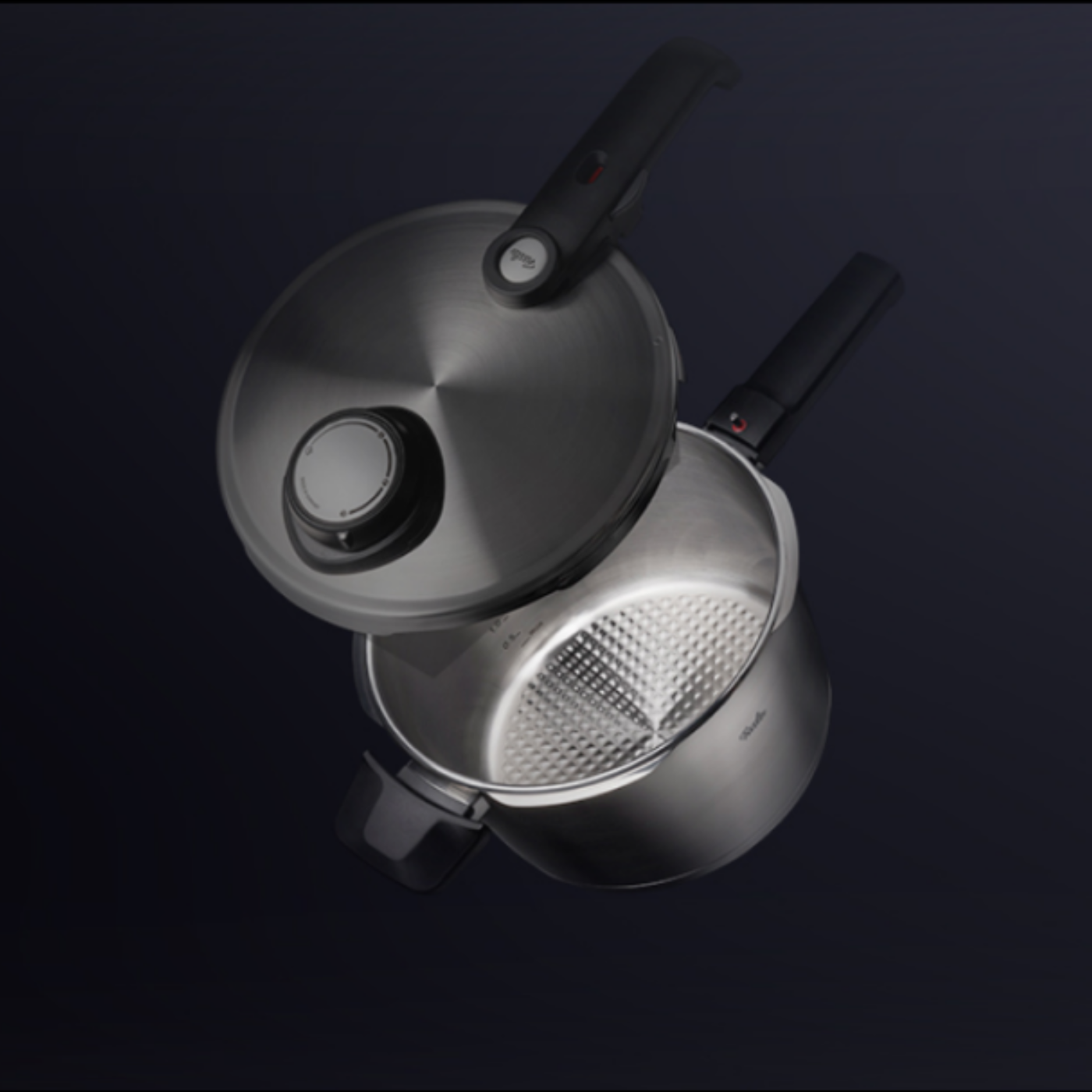 Fissler Schnellkochtopf aus rostfreiem Stahl mit schwarzem Griff. Der Deckel ist teilweise geöffnet und gibt den Blick auf das präzise strukturierte, in Deutschland hergestellte Innere frei.