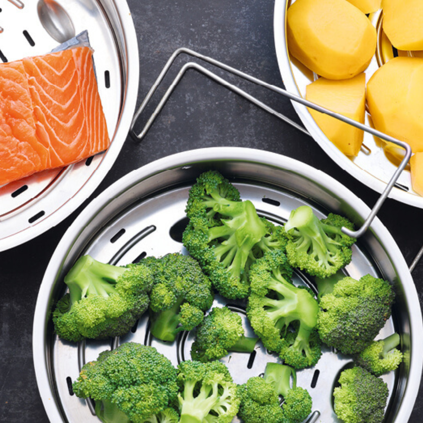 Draufsicht auf Fissler-Edelstahl-Dampfgarer mit Brokkoli, Kartoffeln und Lachs, die deutsche Präzision und Qualität demonstrieren.