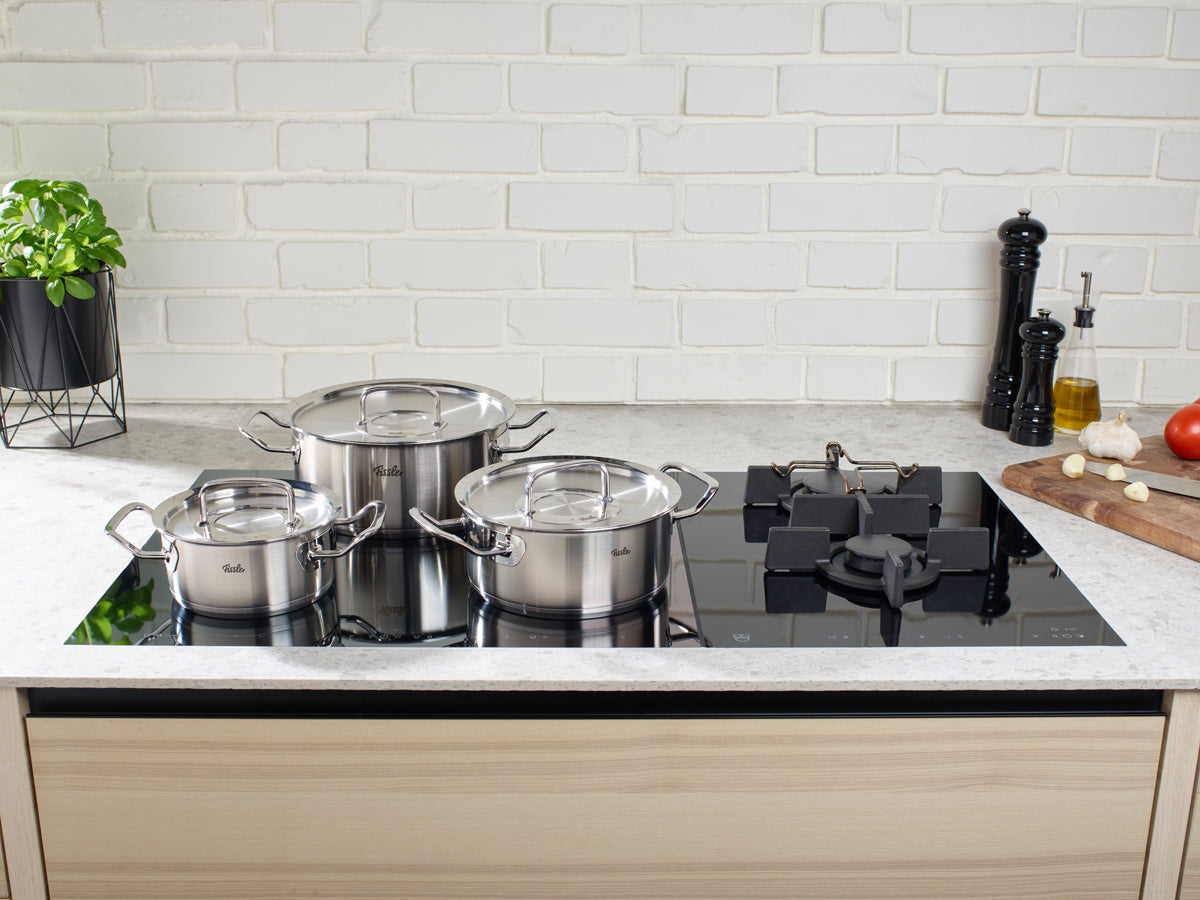 Three Fissler Original-Profi Collection® stew pots on an induction hob in a minimalist kitchen, embodying German precision and design.