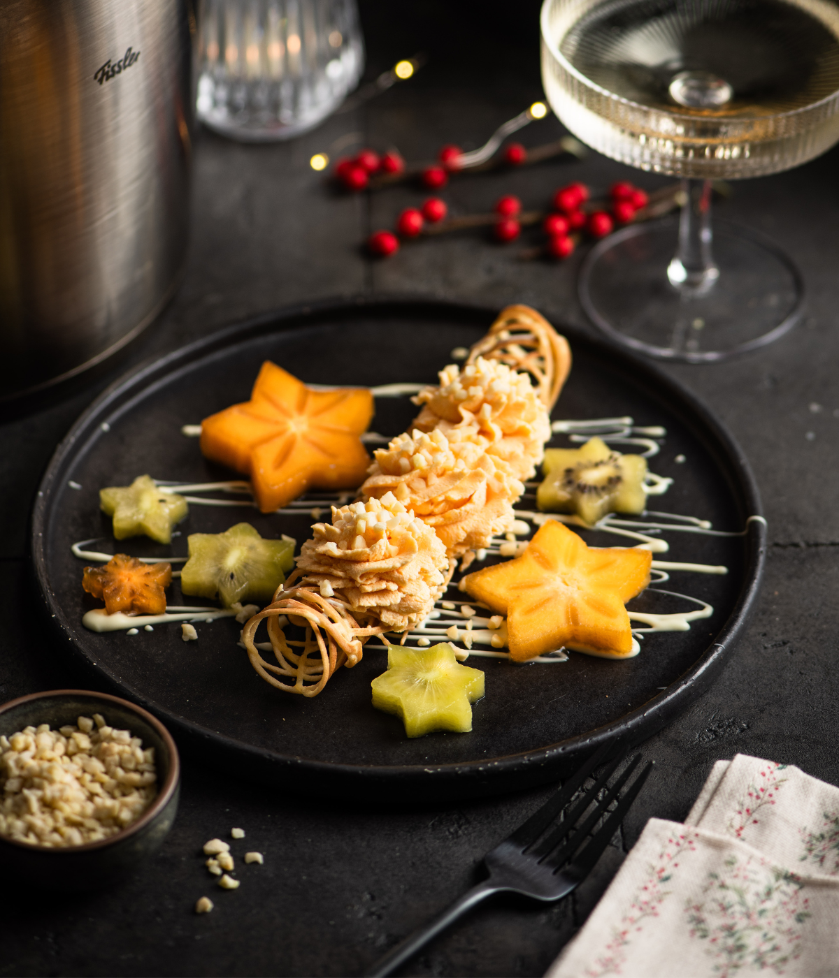 A dessert crafted with pastry rolls, fruit stars, and sauce – made with Fissler cookware. Champagne and decor in the background.