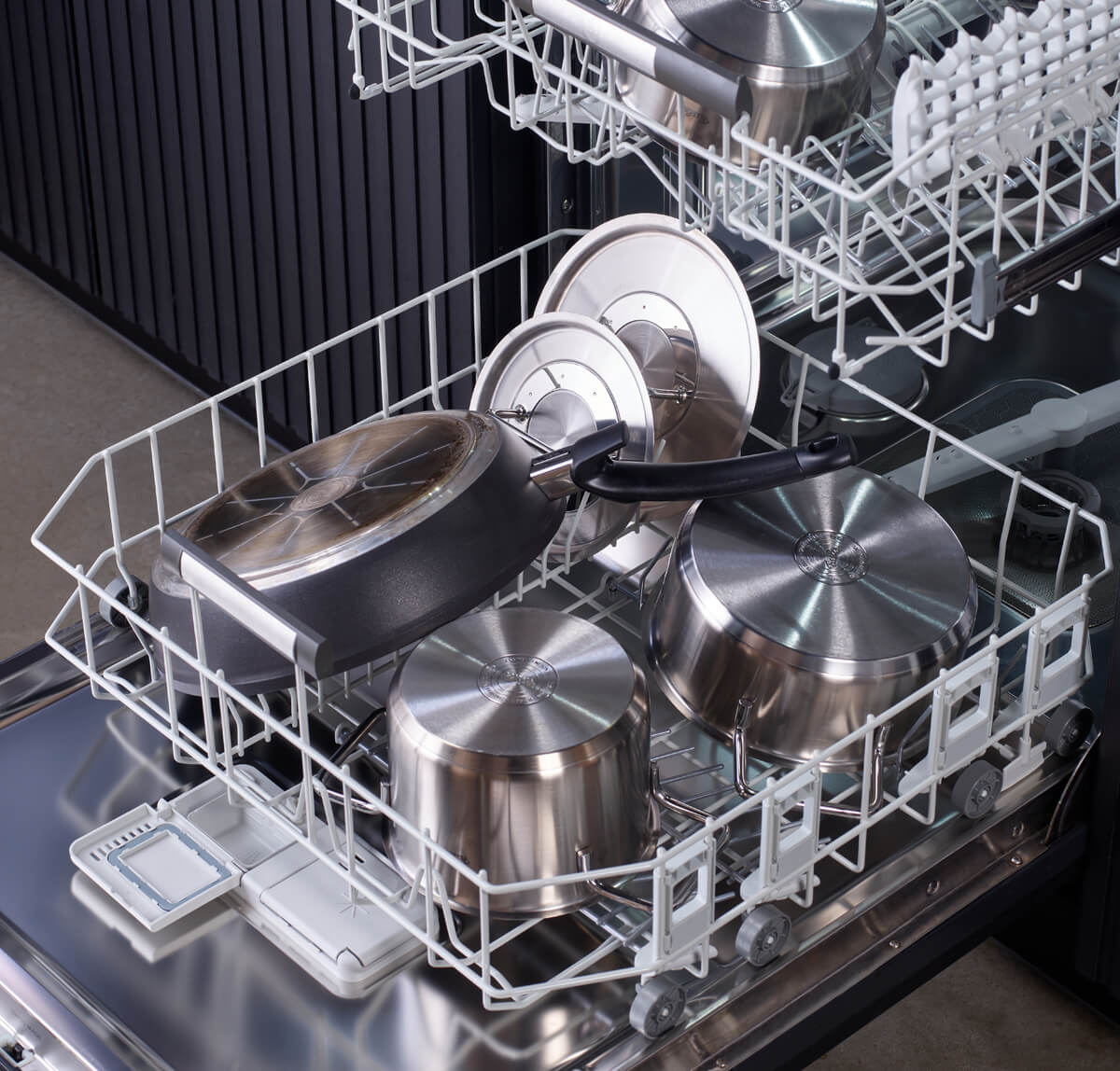 Open dishwasher with Fissler Adamant® Comfort 2-piece Frying Pan Set, scratch-resistant, in a modern kitchen with black metallic accents.