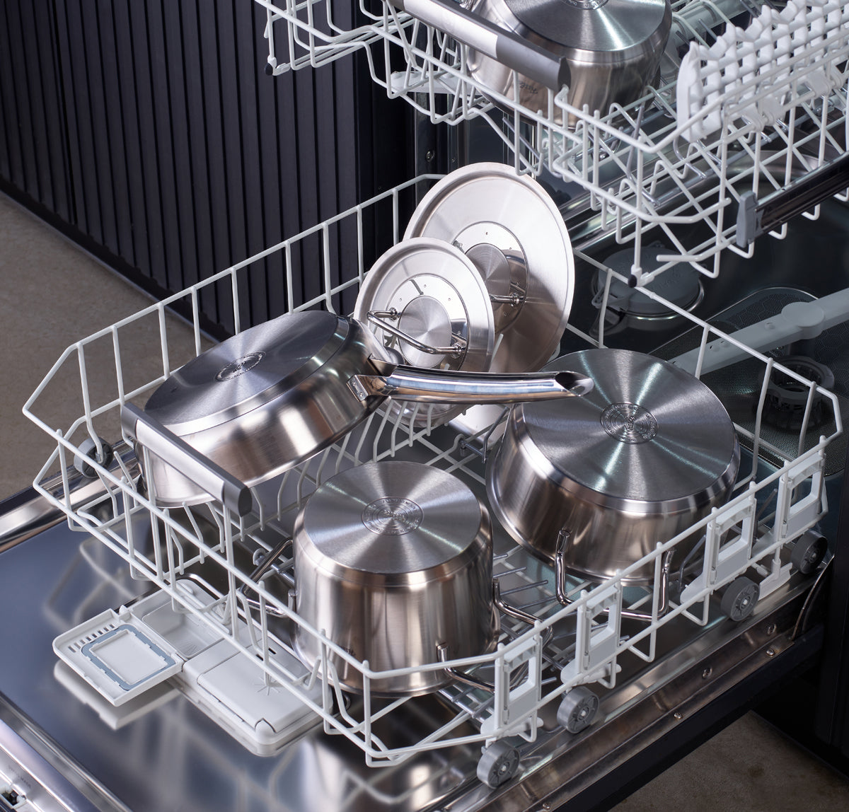 Open dishwasher with pots, pans, and lids from the Fissler Pure Collection made of stainless steel on shelves - a sign of quality from German production.