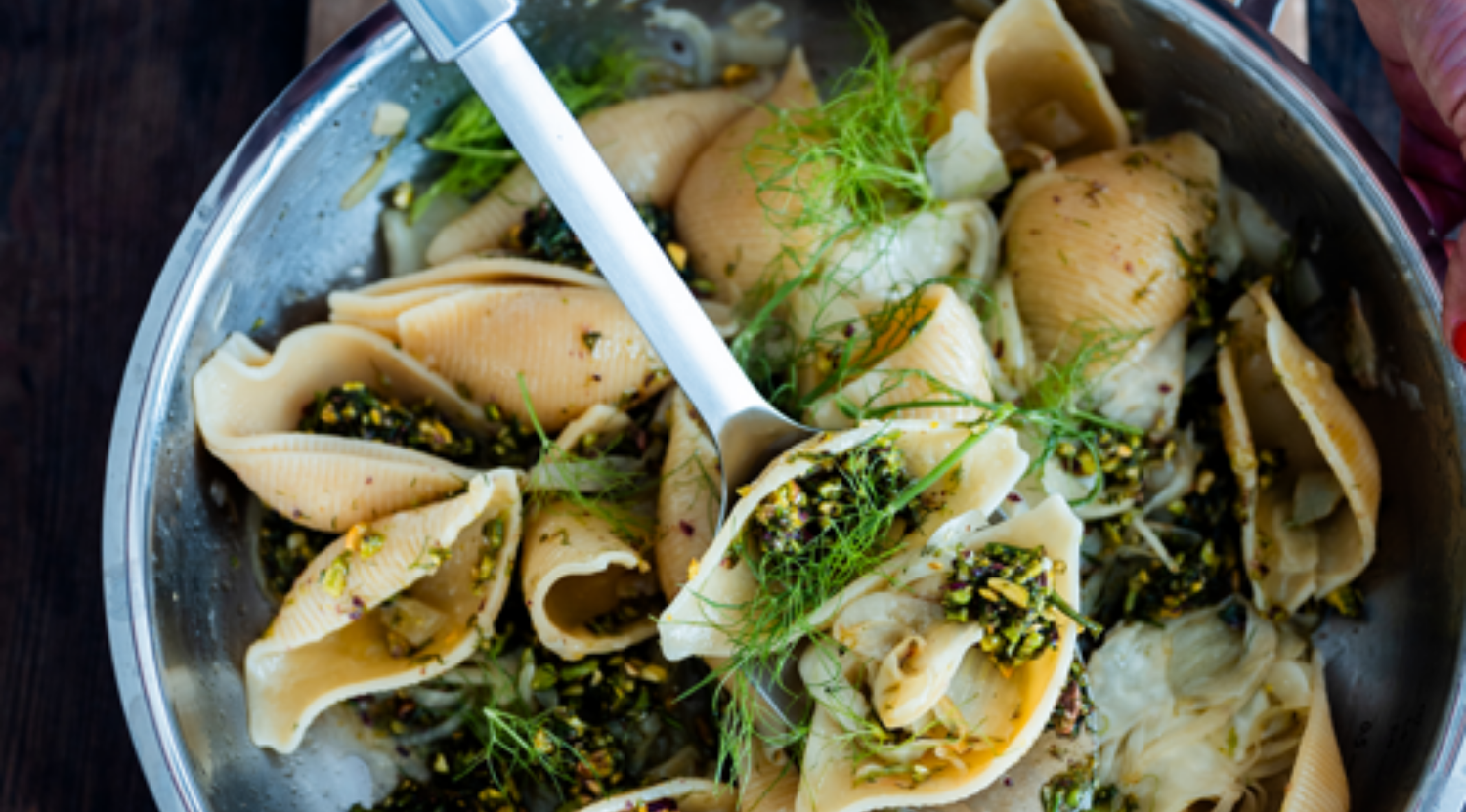 Fissler-Edelstahlpfanne mit gefüllten Nudelschalen, grüner Kräuterfüllung, frischer Dillgarnitur und Silberlöffel zum Servieren.
