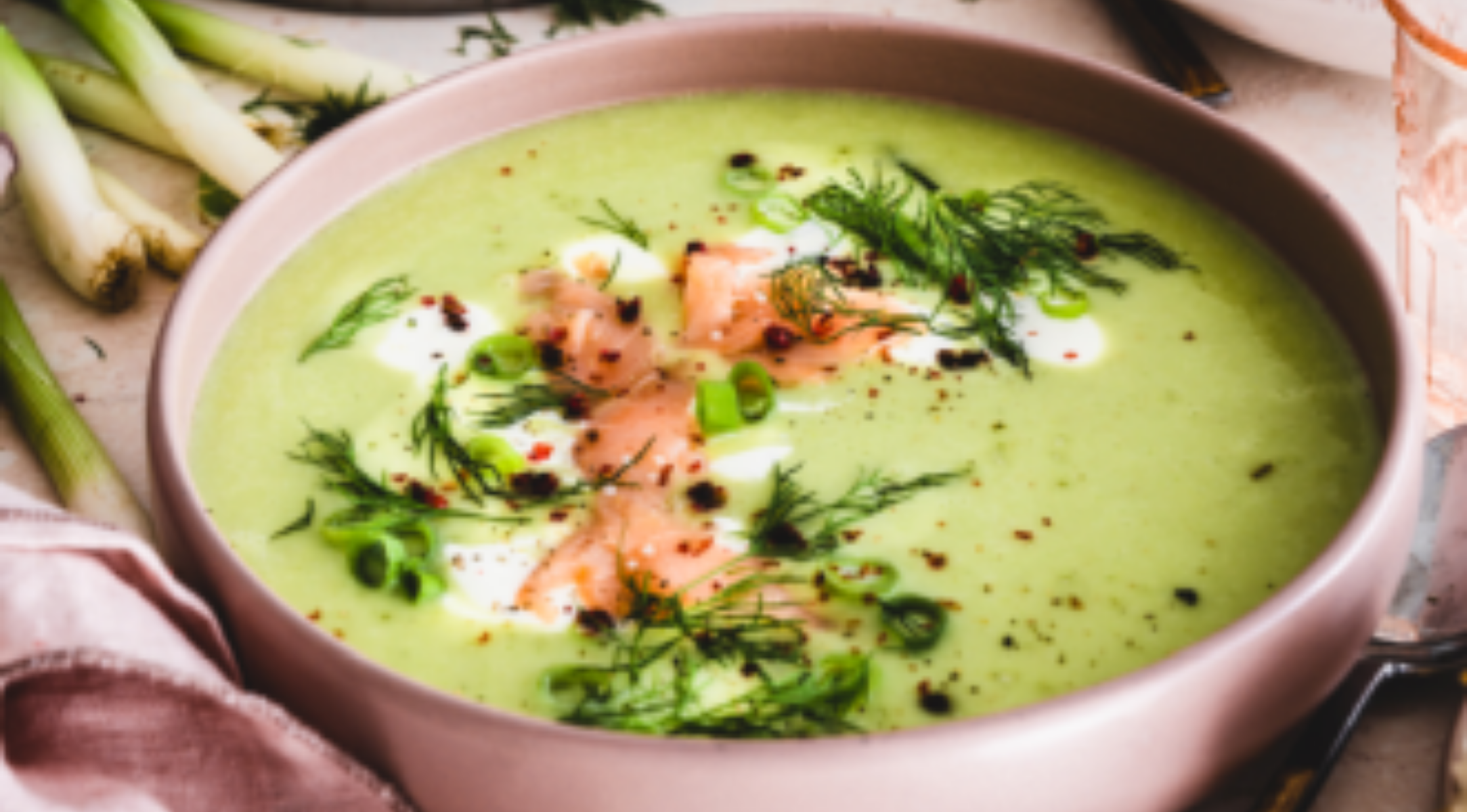 Grüne Cremesuppe mit Lachs und Kräutern, elegant präsentiert in einer rosafarbenen Schale, zubereitet mit dem Präzisionskochgeschirr von Fissler.