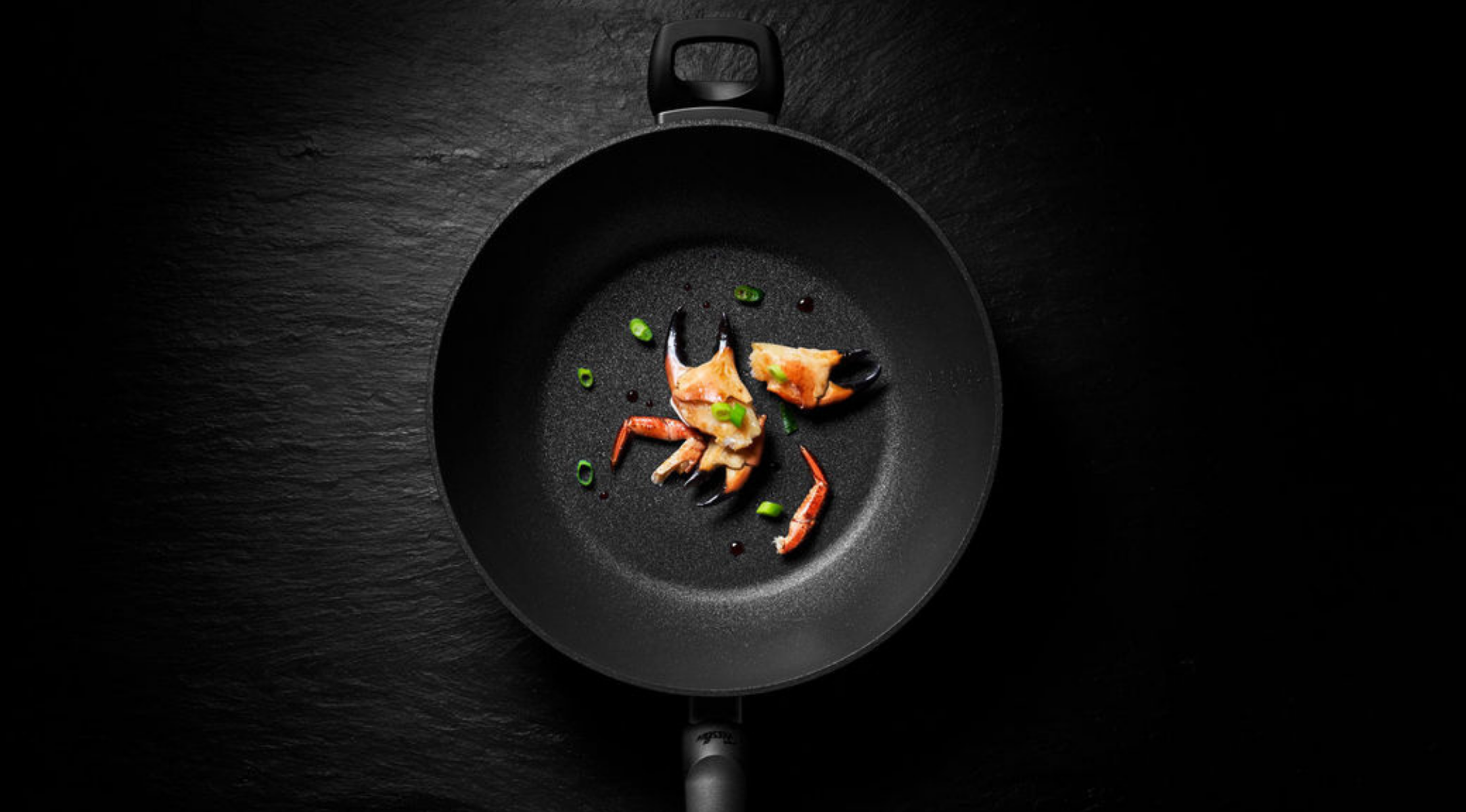 In einer antihaftbeschichteten Bratpfanne von Fissler werden Krabbenfleisch, eine Krabbenschere und Frühlingszwiebeln präsentiert - präzise gegart und elegant angerichtet.