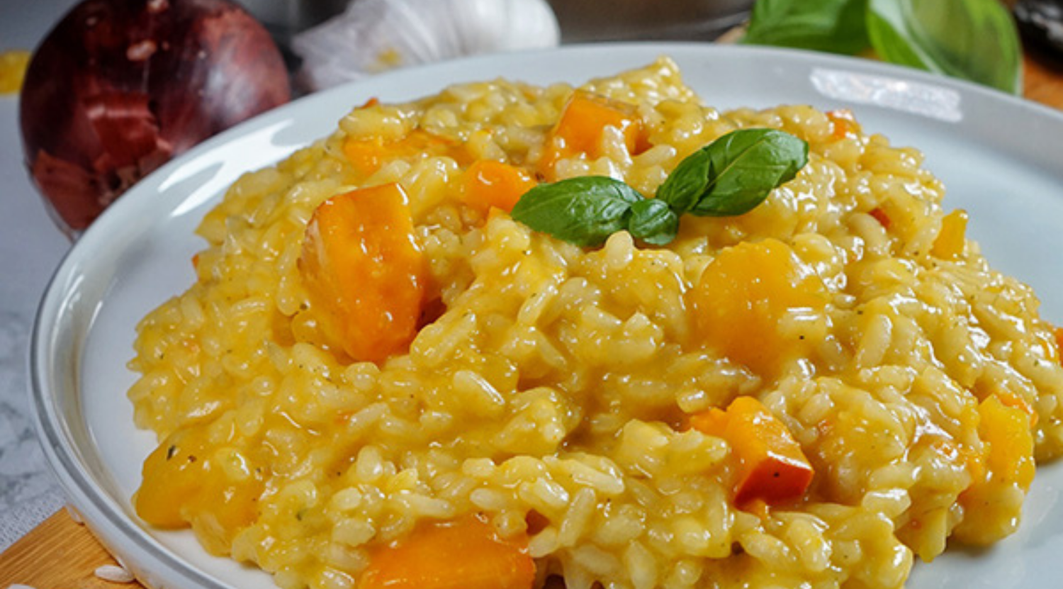 Cremiges Risotto mit lebhaftem Gemüse und Basilikum, elegant angerichtet. Das Kochgeschirr von Fissler sorgt jedes Mal für perfekte Ergebnisse.