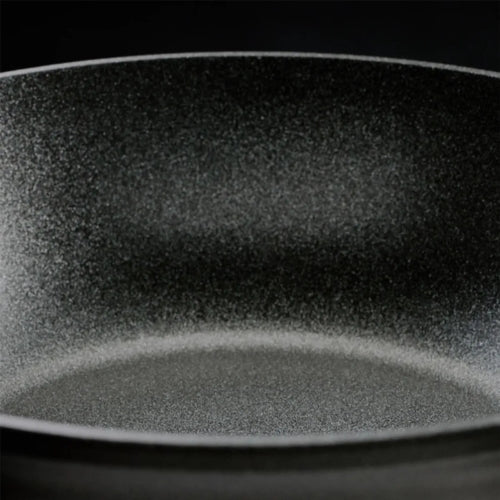 Nahaufnahme einer antihaftbeschichteten Bratpfanne von Fissler mit gesprenkelter, dunkelgrauer Oberfläche, die für Präzision und Langlebigkeit entwickelt wurde.