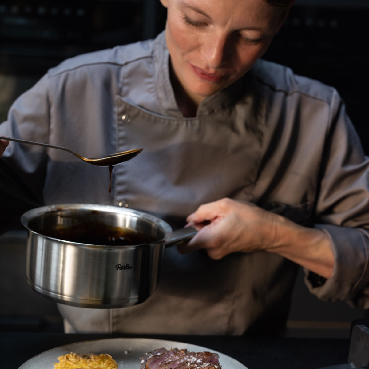A chef uses the Fissler stainless steel pot, made in Germany, for drizzling sauce, highlighting precision and timeless cookware design.