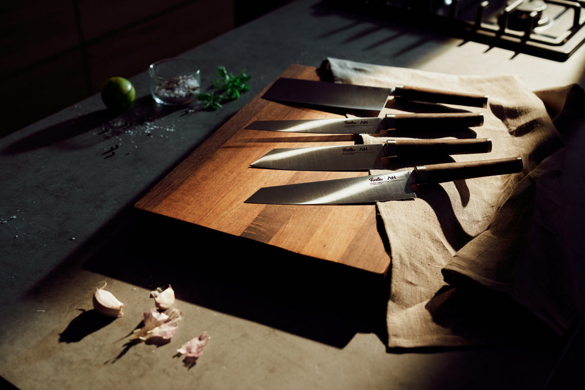 Fissler PrimeCut 18cm Chinese Chef's Knife on wooden board, gray counter, with fresh ingredients - timeless German precision.