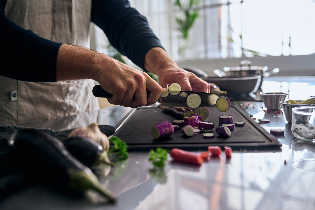 A chef cuts eggplants with the Fissler ProCut chef's knife 16cm in a modern, bright kitchen equipped with Fissler cookware and tools.