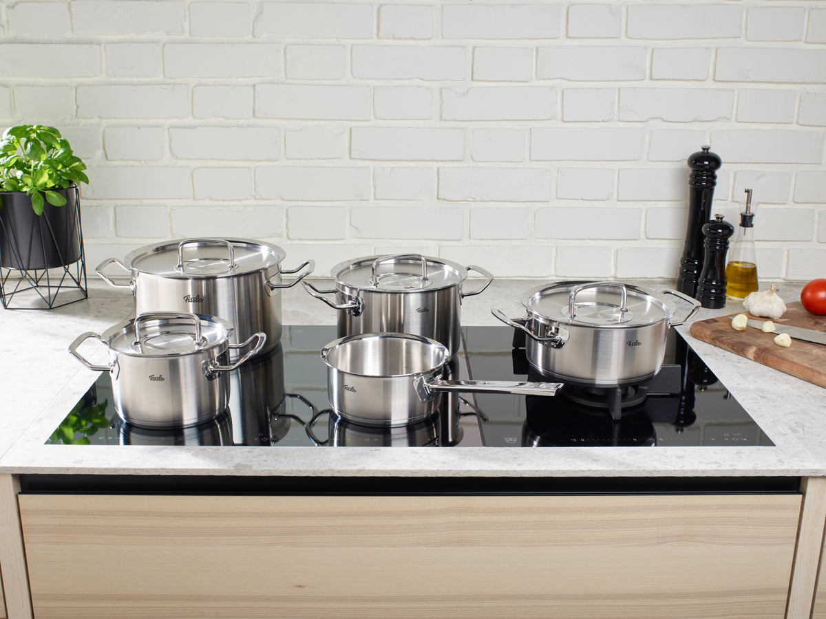 Fissler Original-Profi Collection® 5-piece set plus free Frying Pan on black induction cooktop; modern, German-made Premium Cookware.