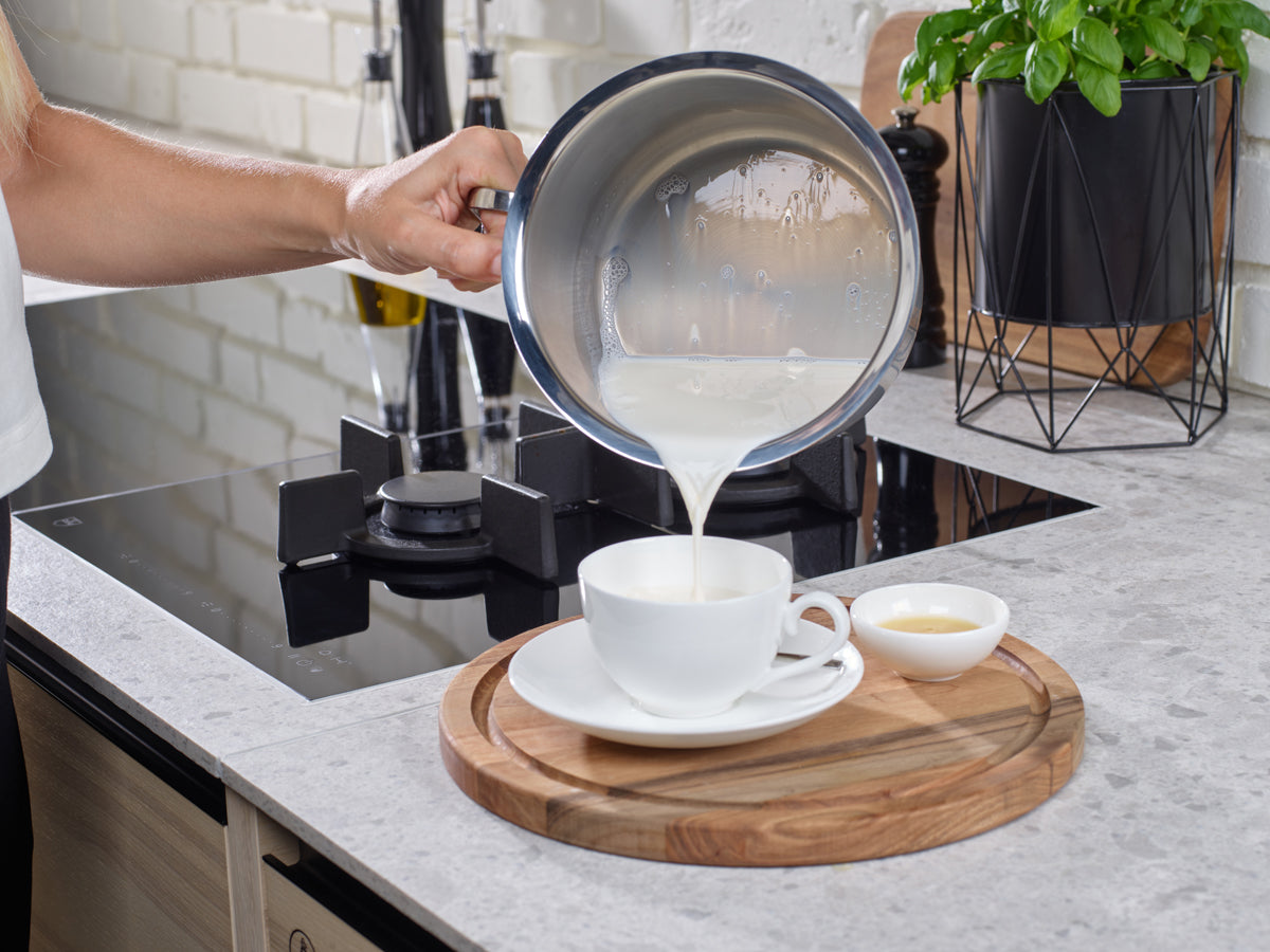 Die Milch wird aus einem Fissler Original-Profi Collection® 16cm Milchtopf in eine Teetasse gegossen und zeigt Qualität und Design aus deutscher Produktion.