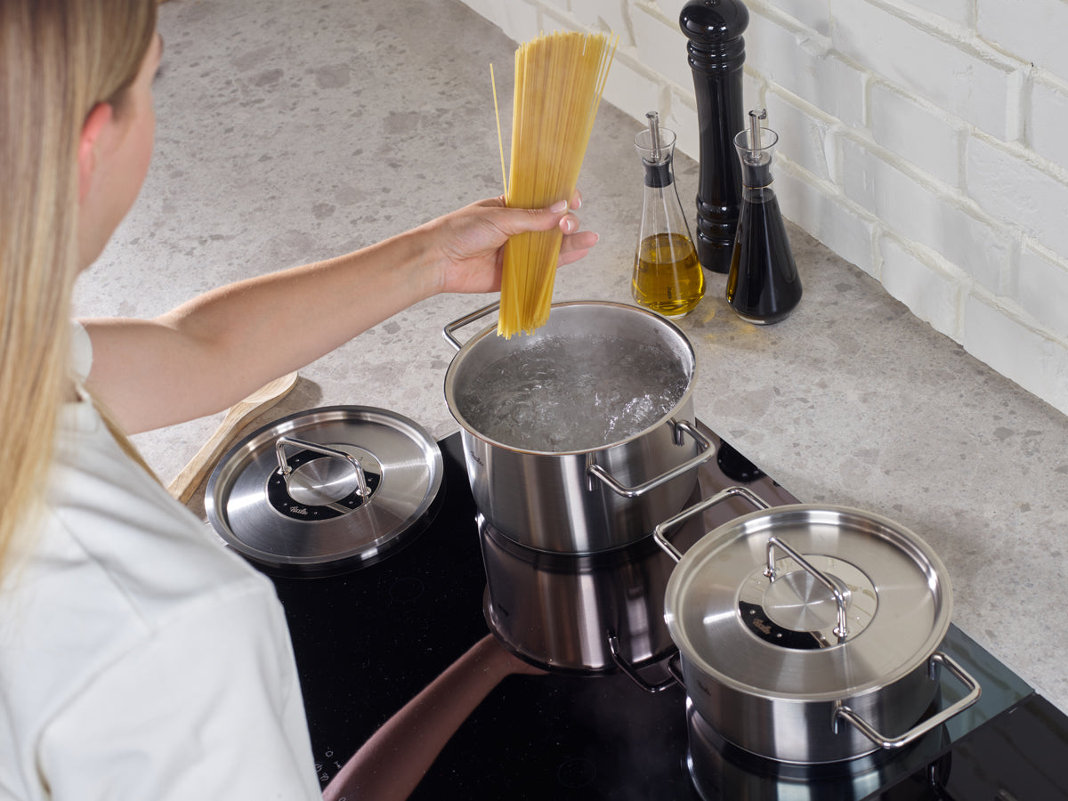 Eine Person am Herd bereitet Spaghetti mit den Töpfen der Fissler Pure Collection® zu - hochwertiges deutsches Kochgeschirr für zeitloses Kochen zu Hause.