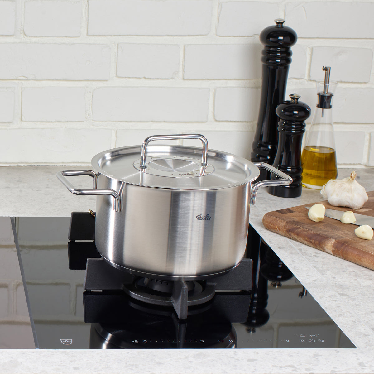 Fissler Pure Collection Cooking Pot on induction cooktop, marble countertop. Stainless steel, Made in Germany. Timeless design.