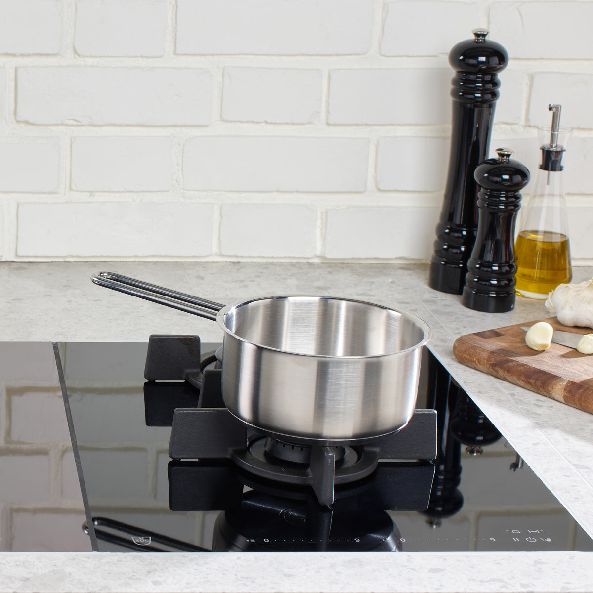 Fissler Pure Collection 16 cm Cooking Pot made from recycled stainless steel on a gas stove, with kitchen utensils in a simple, modern setting.