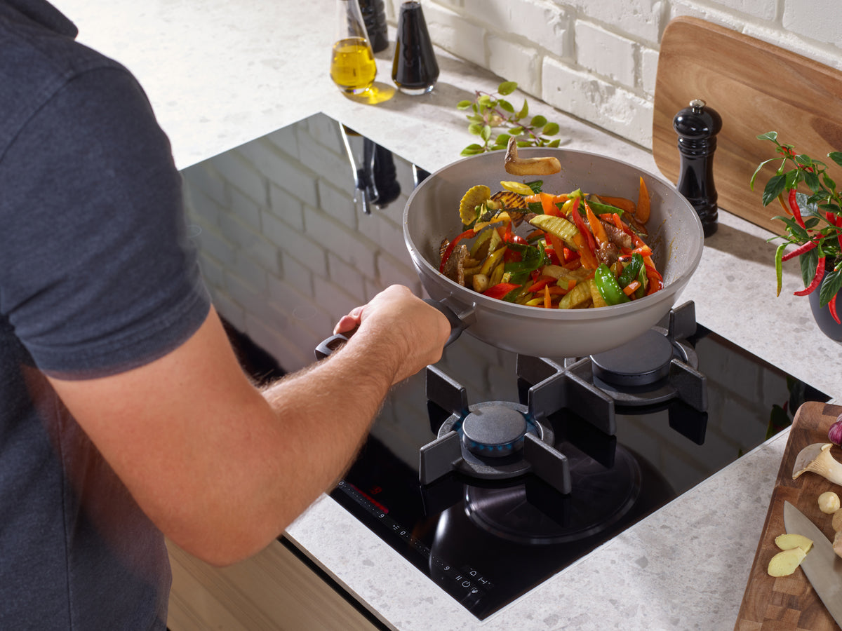 Kochen Sie ein farbenfrohes Wokgericht im Fissler Ceratal® Wok - langlebige, PTFE-freie deutsche Qualität mit frischen Kräutern und Gewürzen zur Hand.