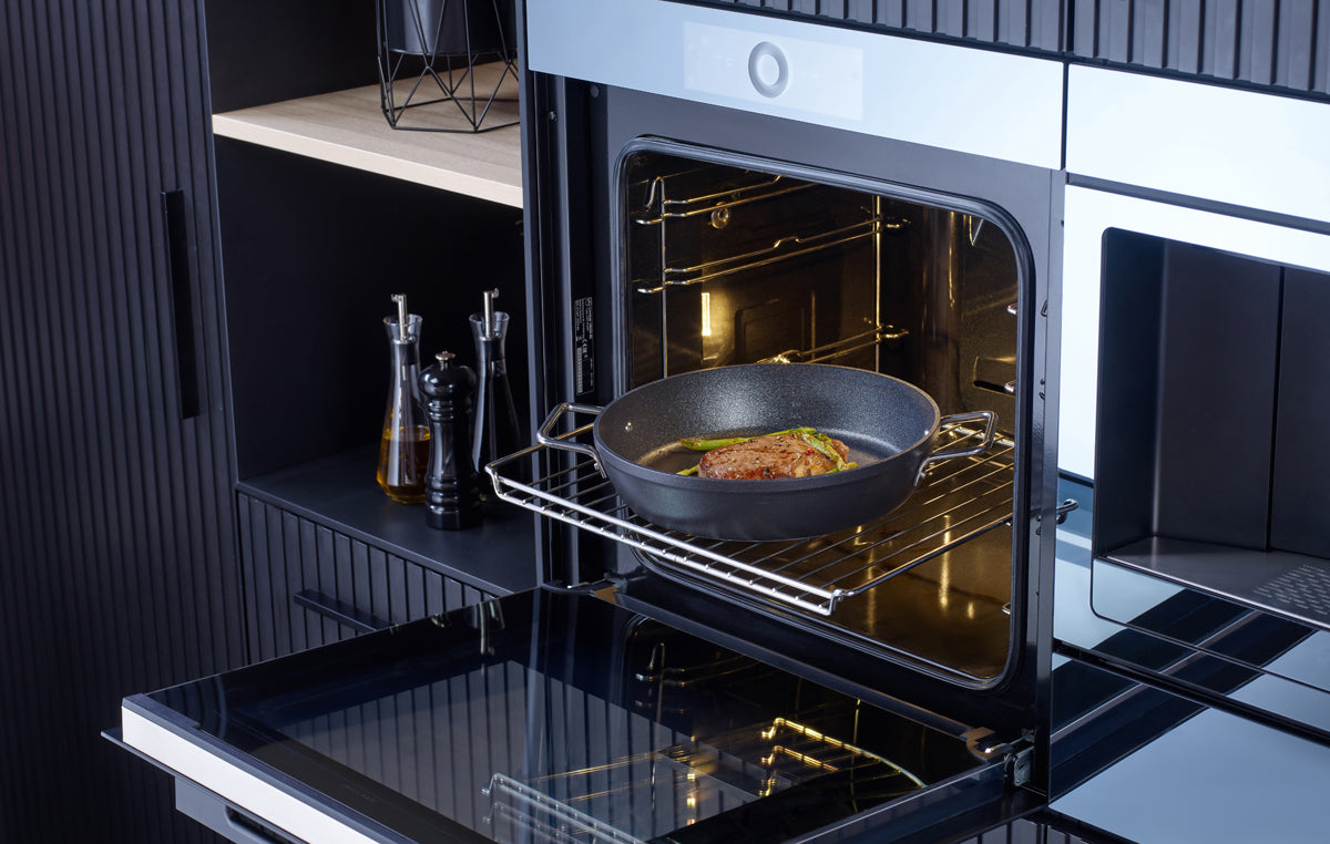 A roast cooks in a Fissler Adamant® serving pan - precision-crafted, non-stick, in an open oven in a modern German kitchen.