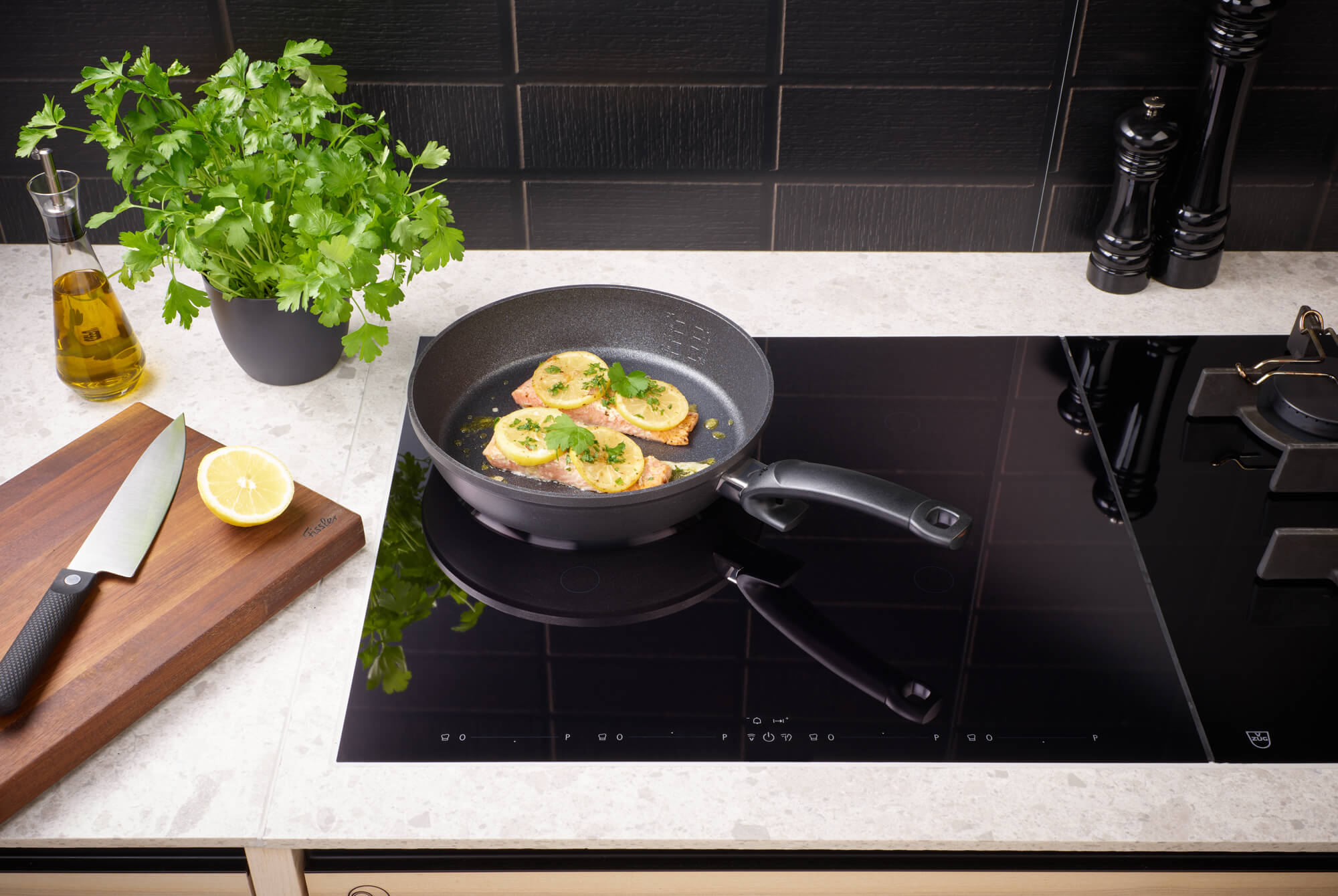 Fissler Adamant® Comfort Frying Pan Set (24 cm & 28 cm) on an induction hob, fresh ingredients within reach; German precision since 1845.