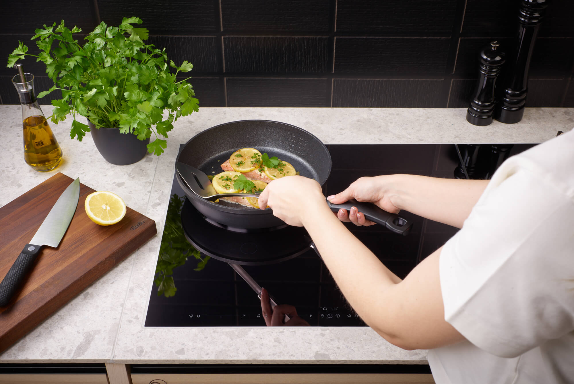 Garen von Hähnchenbrust in Fissler Adamant® Comfort Pfannen; Petersilie, Zitrone, Öl und Kochmesser - Präzision trifft deutsche Qualität.