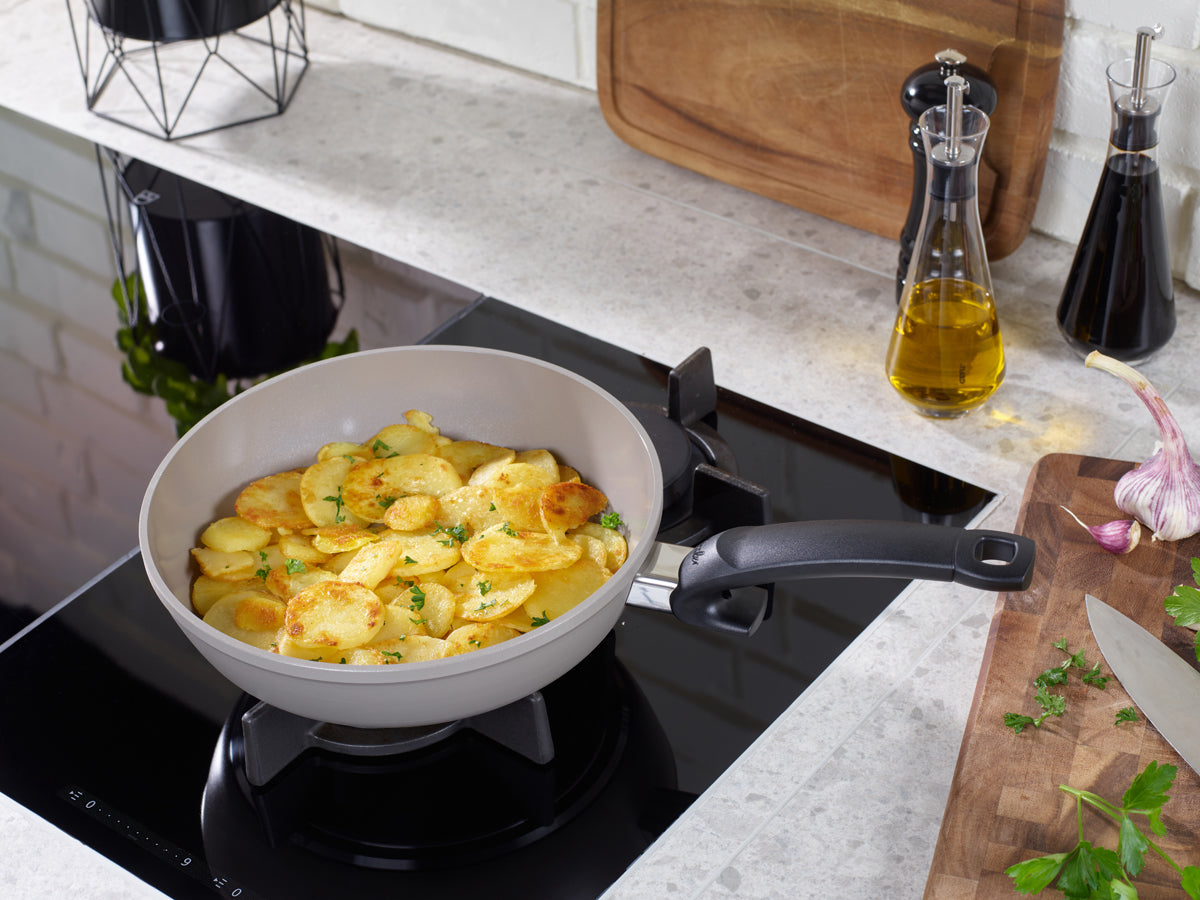 Goldene Kartoffeln kochen in Fissler Ceratal® Comfort PFAS/PTFE-freien Pfannen, 24 & 28 cm. Deutsche Qualität seit 1845. Küchenvorbereitung gezeigt.