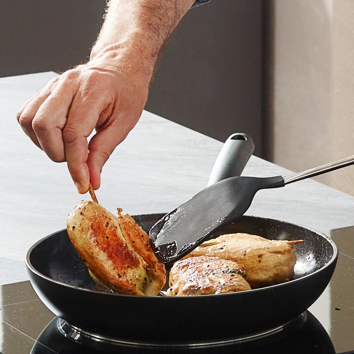 Gefüllte Hähnchenbrüste werden in einer Fissler Essential® Pfanne mit PFAS/PTFE-freier Antihaftbeschichtung auf einer Herdplatte in Made in Germany-Qualität gewendet.