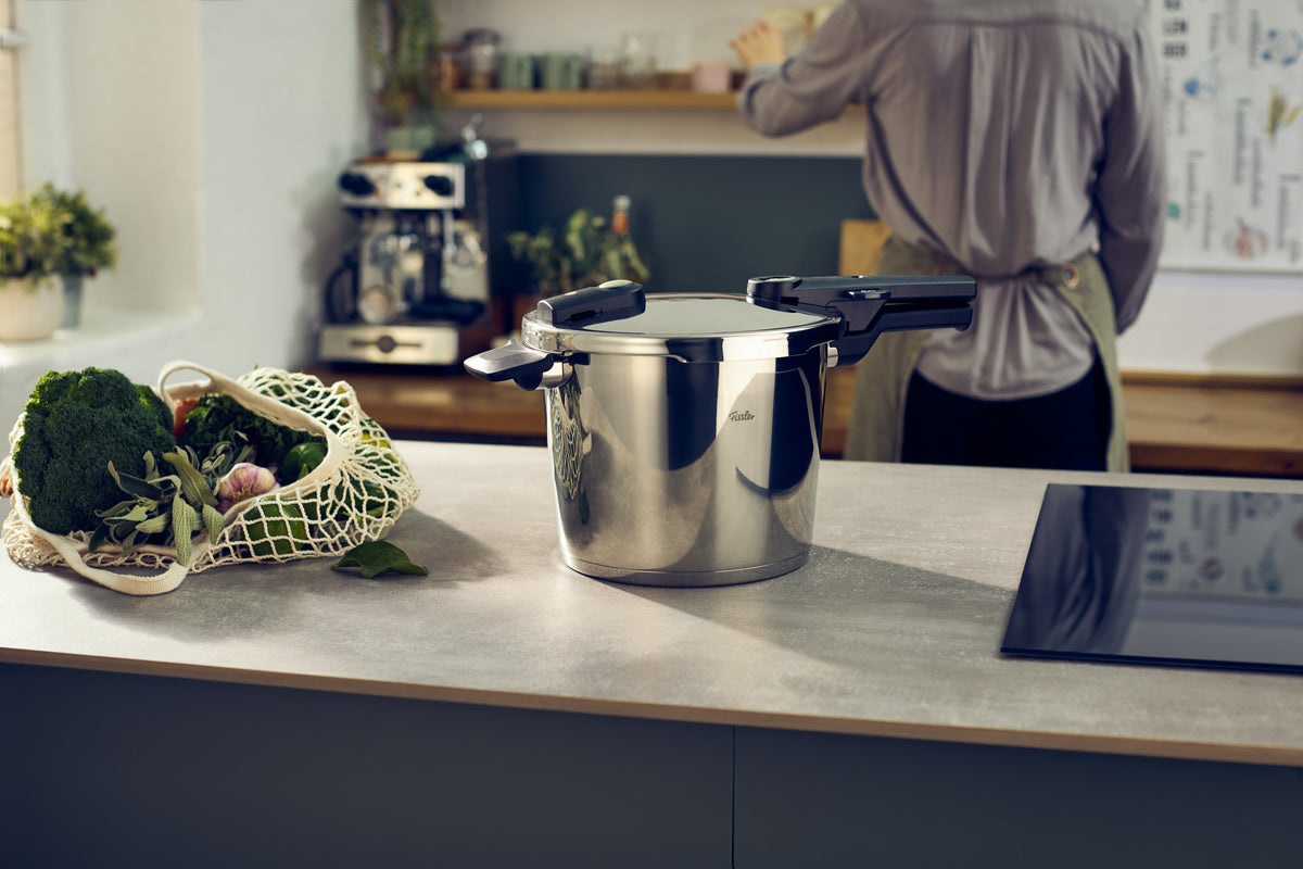Fissler Vitaquick® Elemental 3-pc. pressure cooker set on a counter, near fresh vegetables—precise German cookware since 1845.