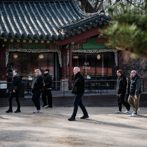 A group of people walk past a traditional Korean building with a sign reading Art Shop. The building’s ornate wooden details and tiled roof reflect a heritage of craftsmanship—an ethos shared by Fissler, where precision engineering and timeless design define every stainless steel pot, pan, and pressure cooker we create.