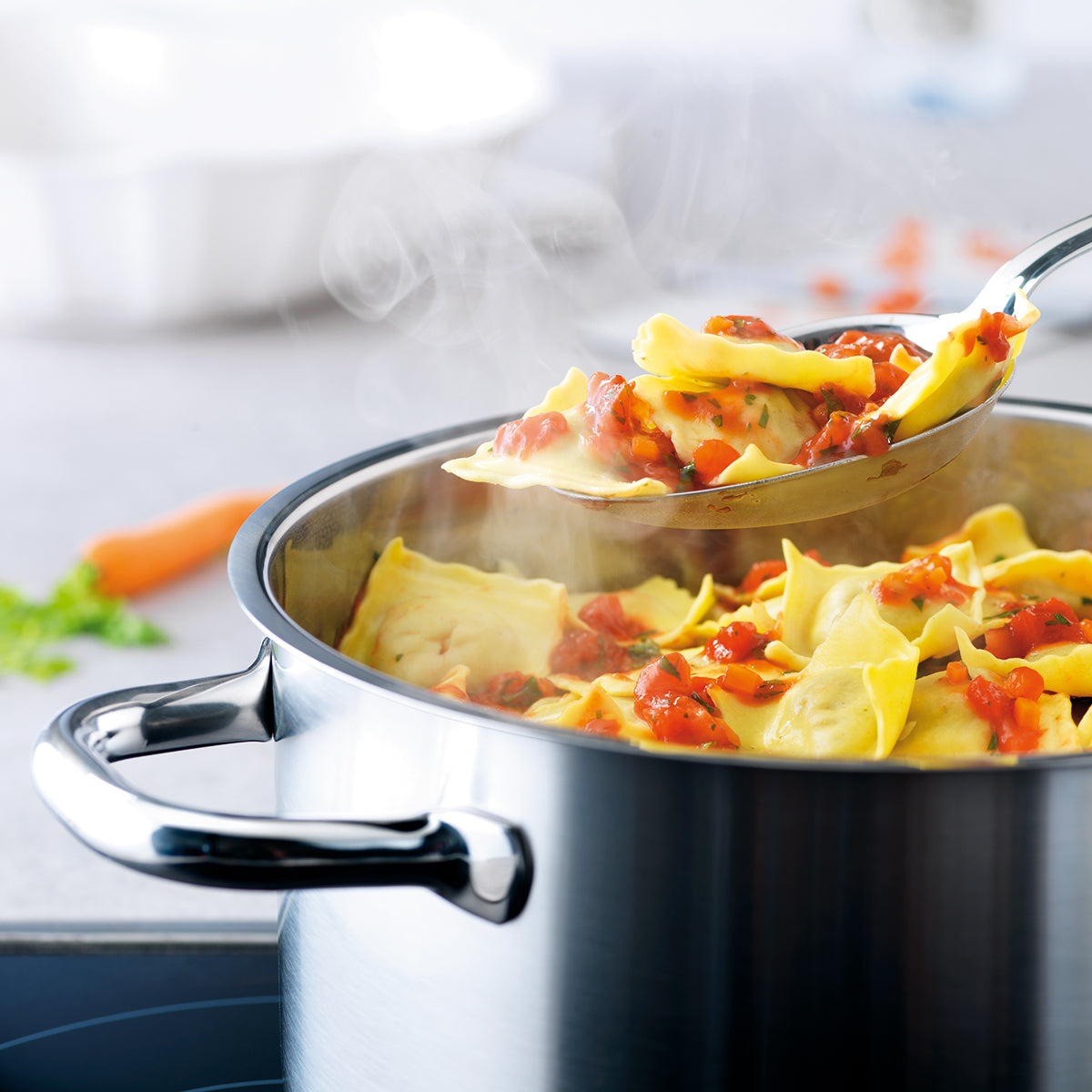 Yellow ravioli in tomato sauce are stirred in a pot from the Fissler Family Line - showcasing precision, durability, and timeless German design.