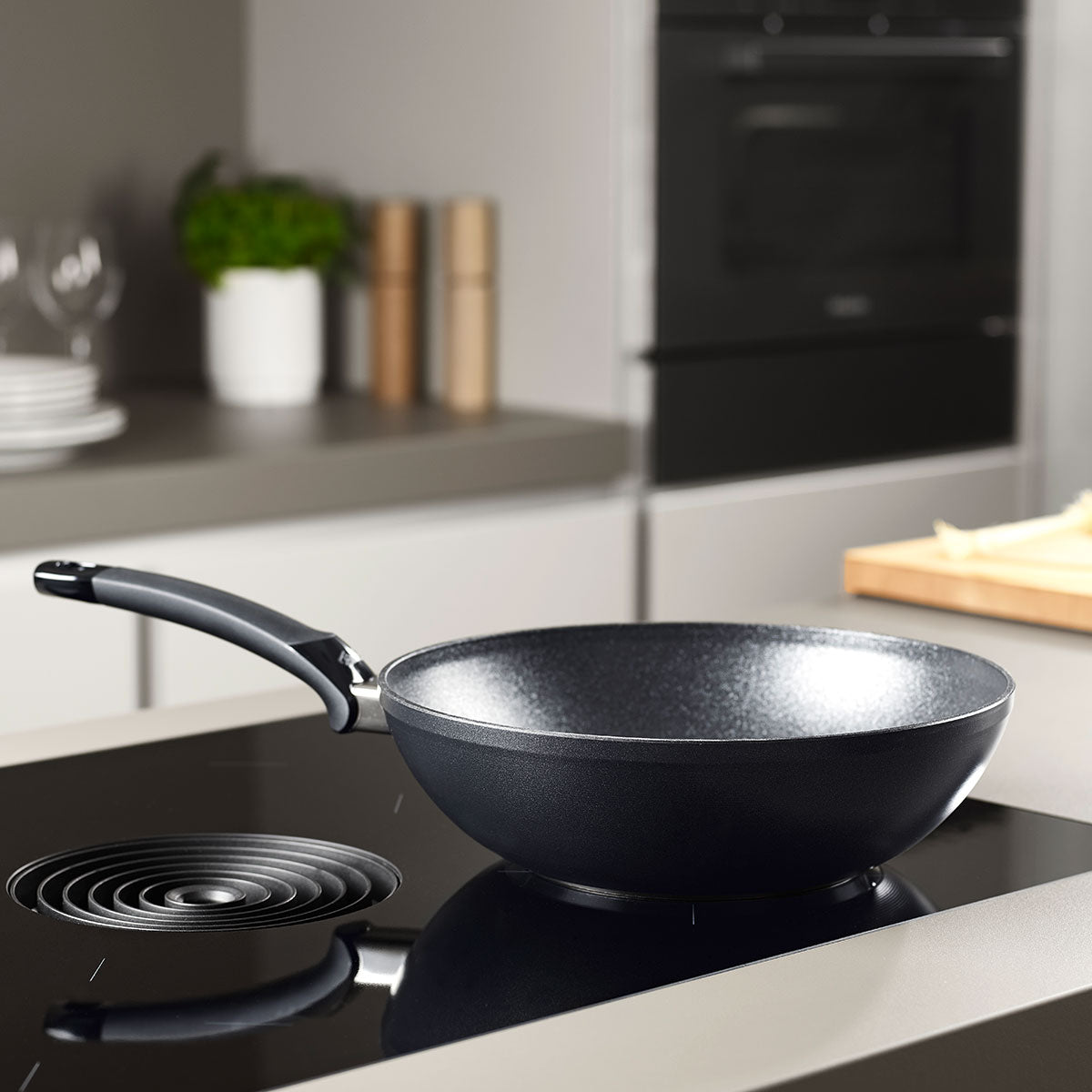 Fissler Adamant® Wok Pan with durable non-stick coating on a modern stove - timeless German design and quality for your kitchen.