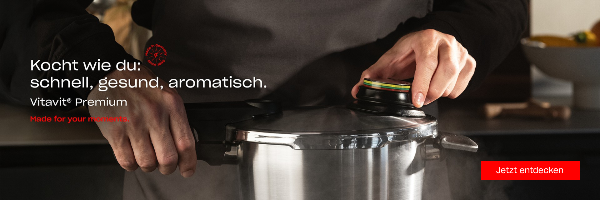 Die Hände schließen den Deckel eines Fissler Vitavit Premium Schnellkochtopfes. Der deutsche Text weist auf schnelles, gesundes Kochen hin. Rote Taste: Jetzt entdecken.