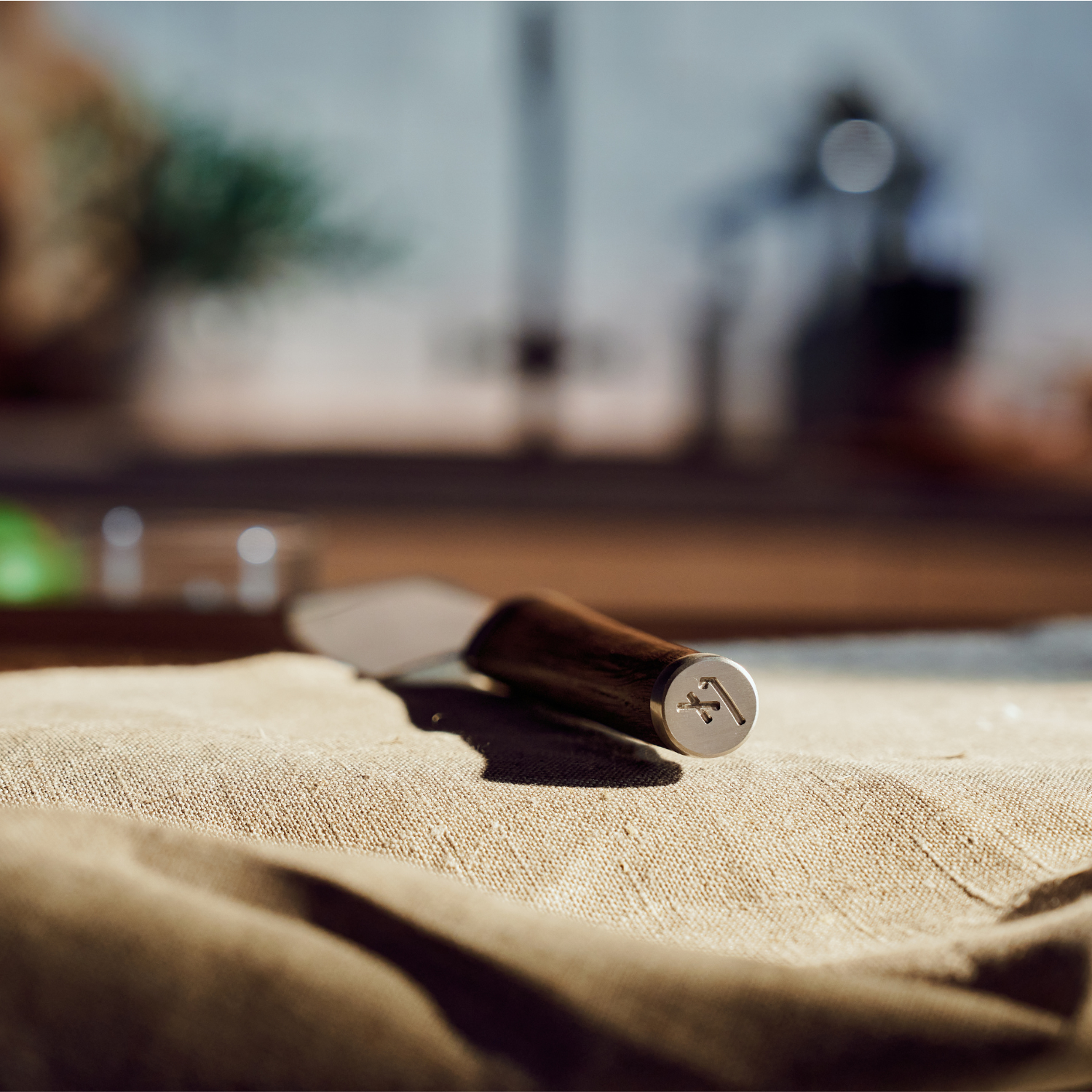 A Fissler kitchen knife with a handmade wooden handle lies on beige fabric, the blade tapers to a point, reminiscent of German quality and design.