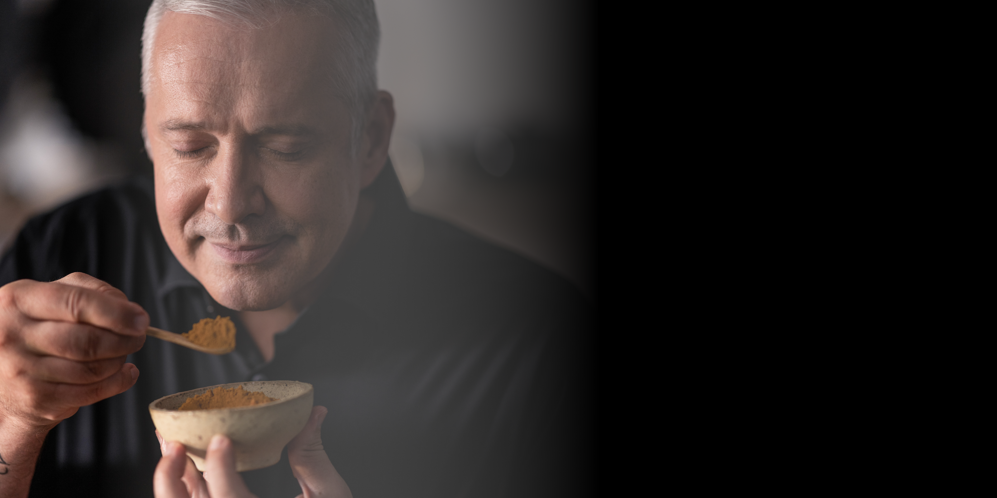 Ein Mann mit grauen Haaren genießt den Duft von Gewürzen und hält eine Schüssel in der Hand - er fängt Fisslers Freude am Kochen mit hochwertigem Kochgeschirr ein.