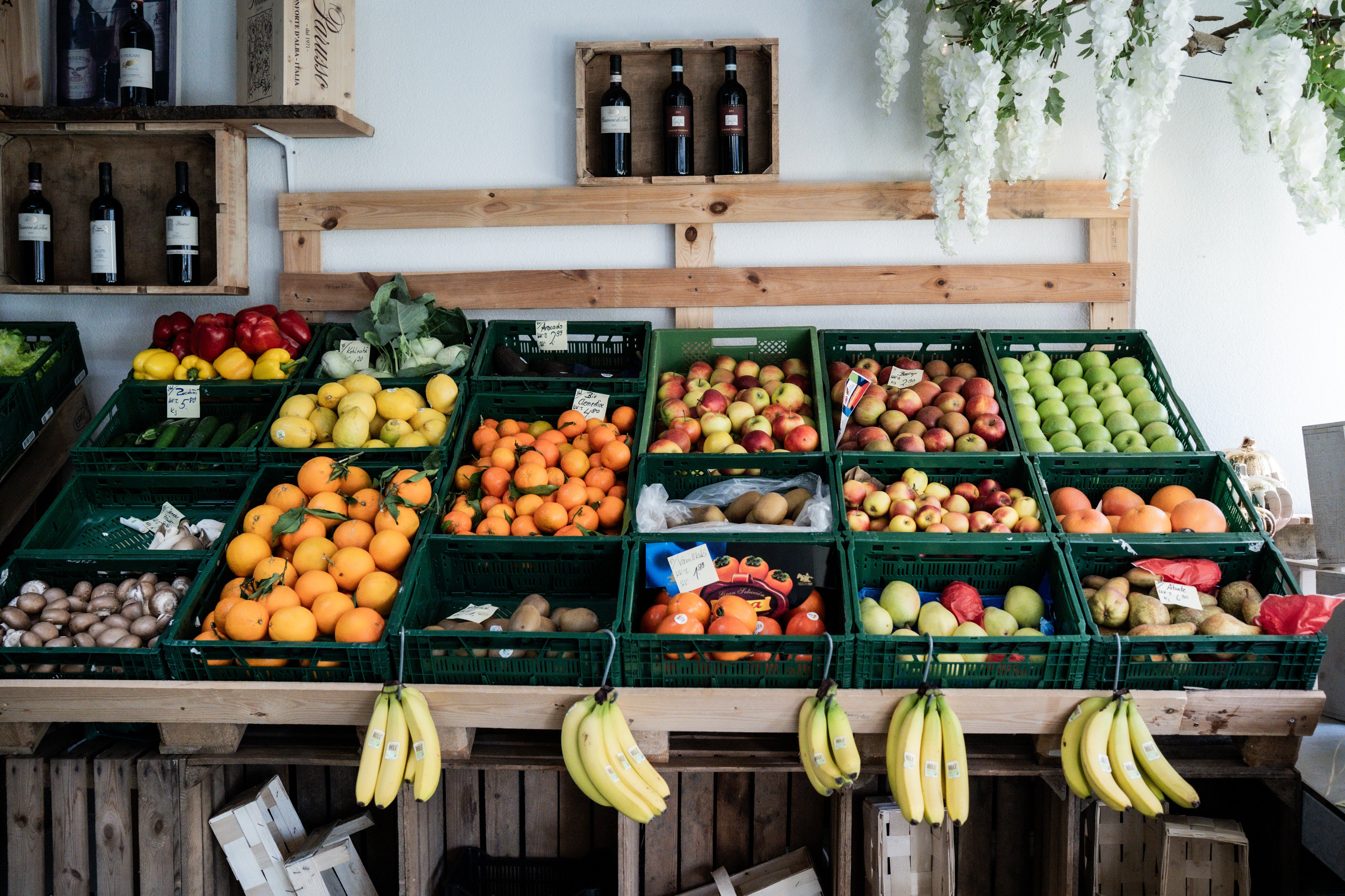 A vibrant market display of fresh fruits and vegetables arranged in baskets next to wine bottles – perfect for Fissler cookware.