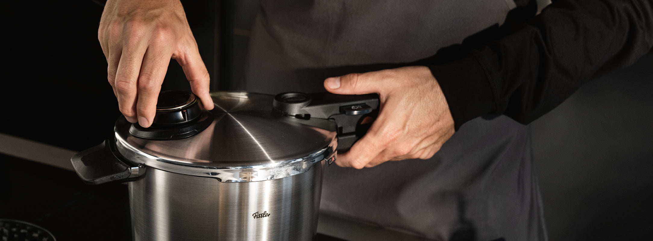 Der Deckel eines Fissler Schnellkochtopfes aus Edelstahl, der deutsche Präzision und zeitloses Design verkörpert, wird von Hand verschlossen.