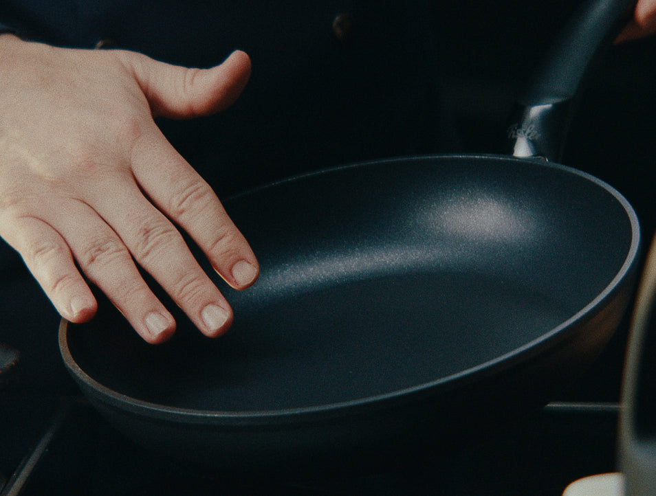 Eine Hand testet die Hitze einer Fissler Antihaft-Pfanne auf dem Herd. Ein Beispiel für deutsche Präzision und zeitloses Kochgeschirrdesign.