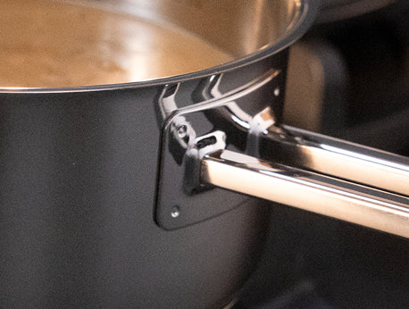 Eine Nahaufnahme eines Fissler-Edelstahltopfs mit Flüssigkeit im Inneren, mit robustem, genietetem Griff - deutsche Präzision in jedem Detail.