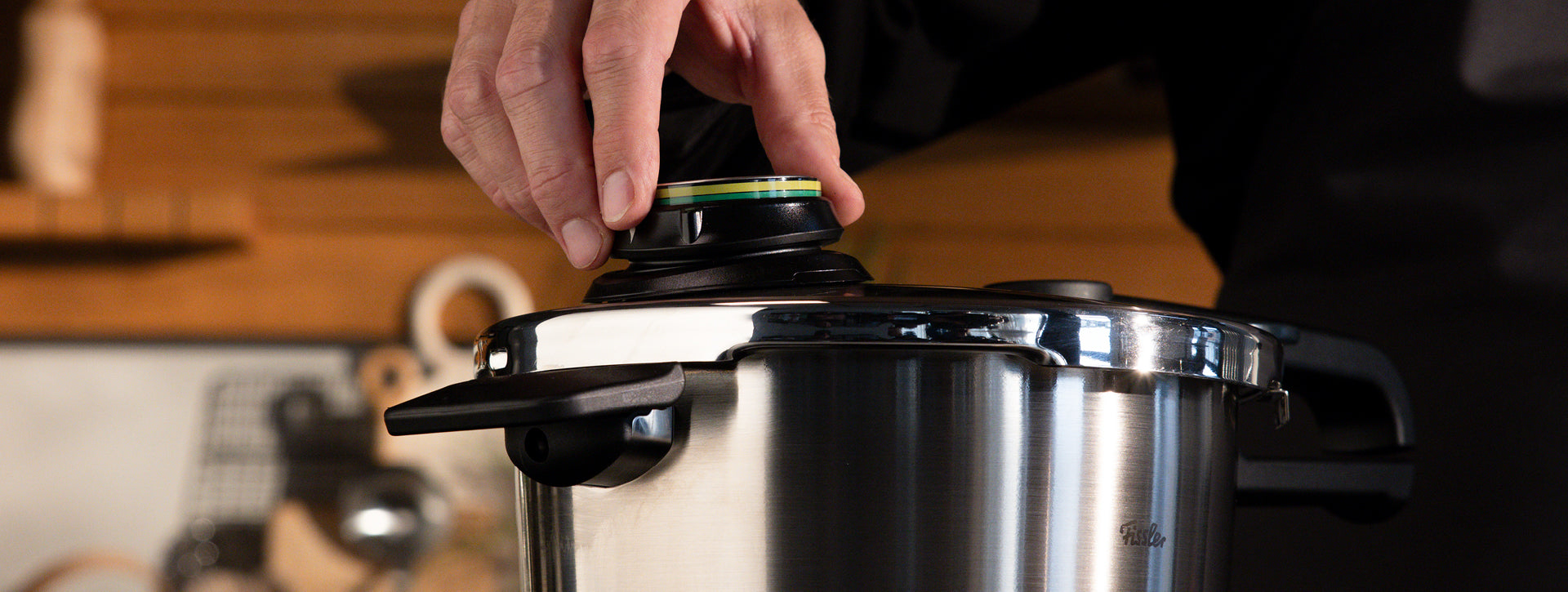 Mit einer Hand lässt sich der Regler des Fissler Schnellkochtopfs aus Edelstahl präzise einstellen, so dass deutsche Ingenieurskunst in einer modernen Küche zur Geltung kommt.