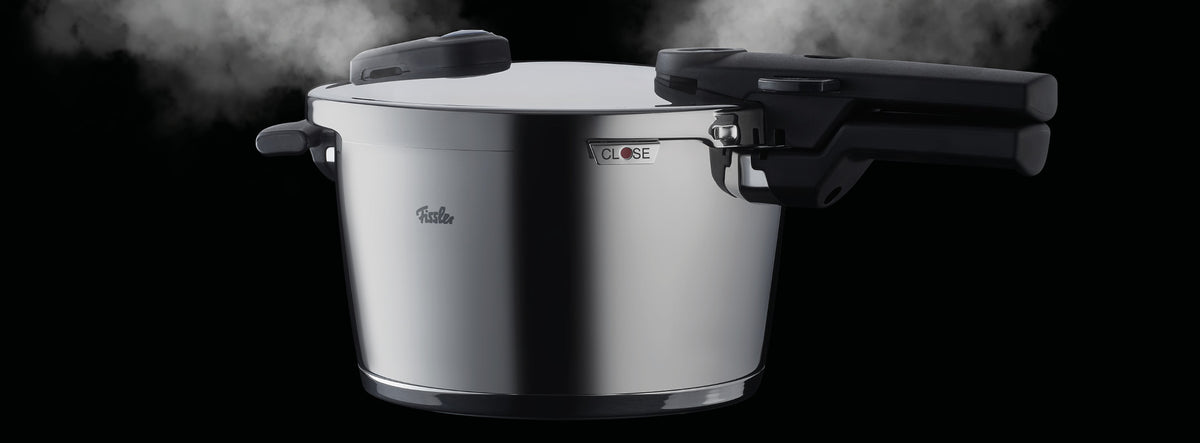 Der Fissler Schnellkochtopf aus Edelstahl mit ergonomischen schwarzen Griffen lässt den Dampf auf beiden Seiten ab und zeigt deutsche Handwerkskunst.