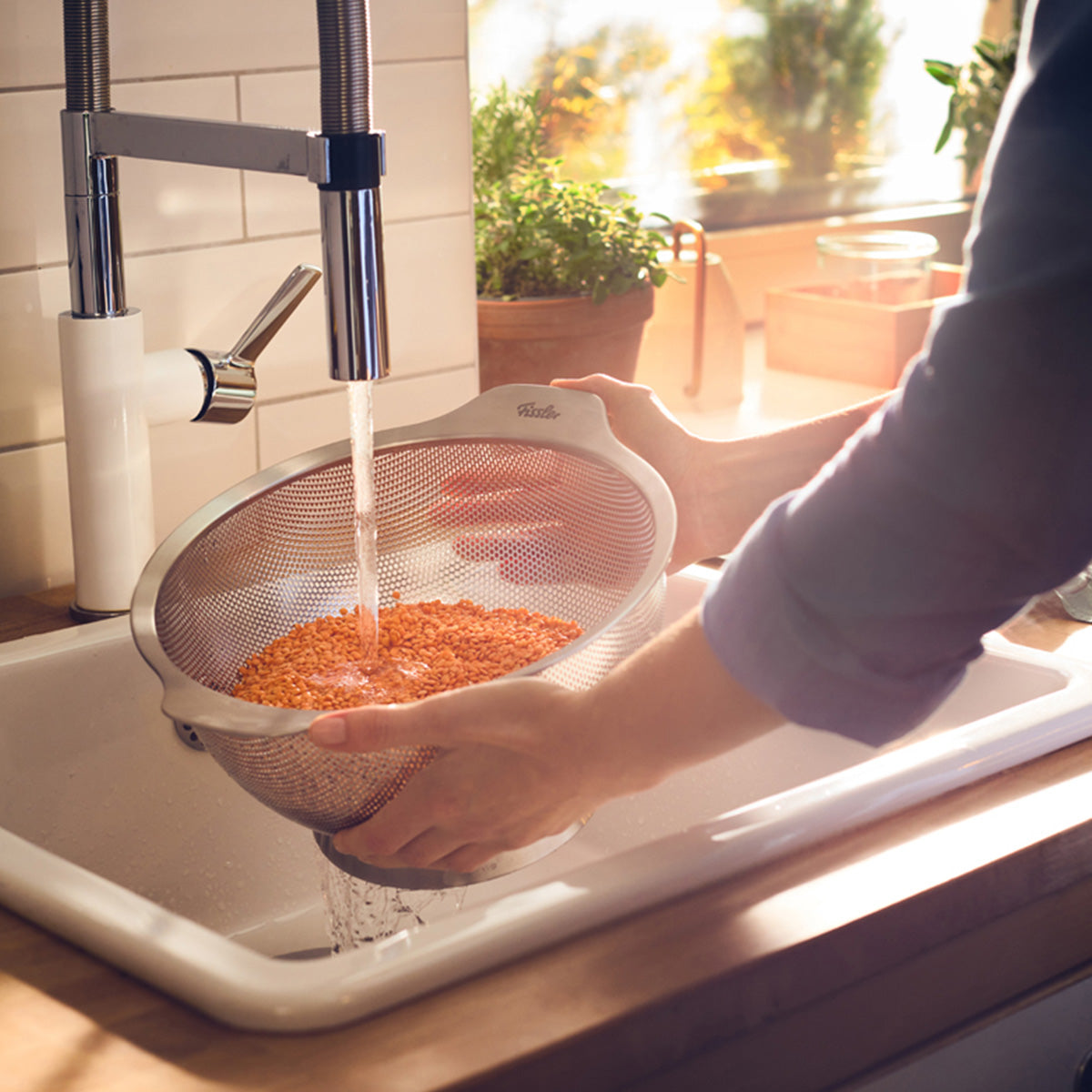 Rinsing red lentils in a Fissler Essential® 24cm stainless steel colander, designed in Germany for lasting precision and quality.